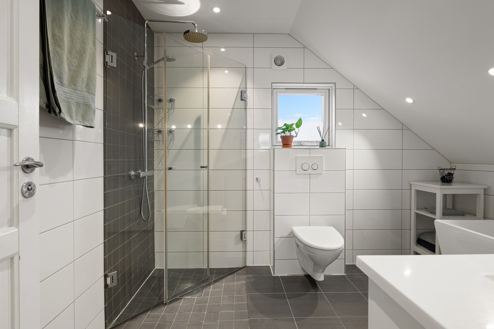 Lyst og lekkert bad fra 2013. På badet har du flislagte gulv og vegger. Varmekabler i gulvet. Tak med innfelte downlights. Rommet er innredet med en servantseksjon med nedfelt vask, veggmontert toalett, badekar og et dusjhjørne Galleribilde