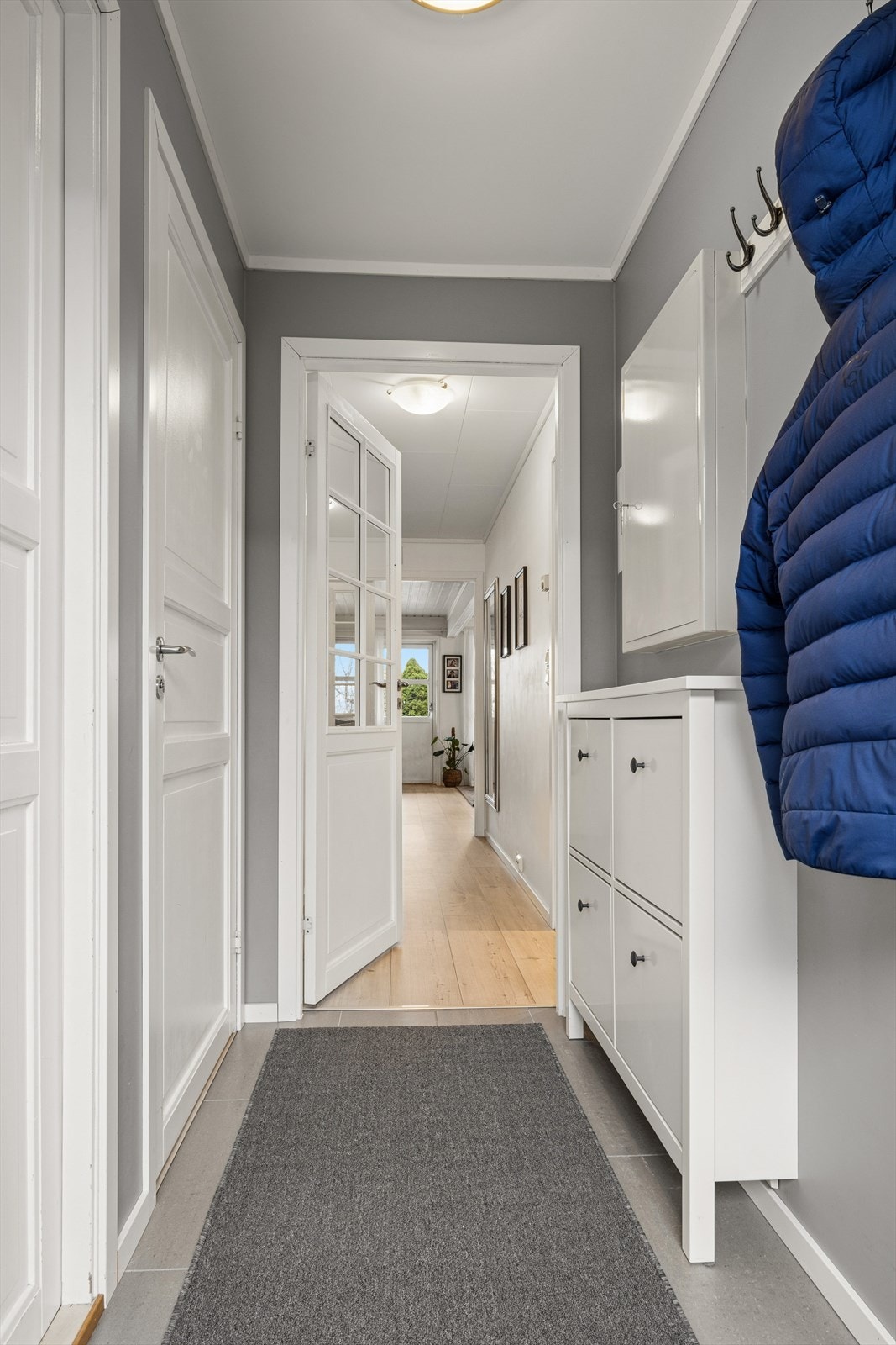 Entreen er lysmalt med flislagt gulv. Inngang fra entreen til et praktisk vaskerom. Galleribilde