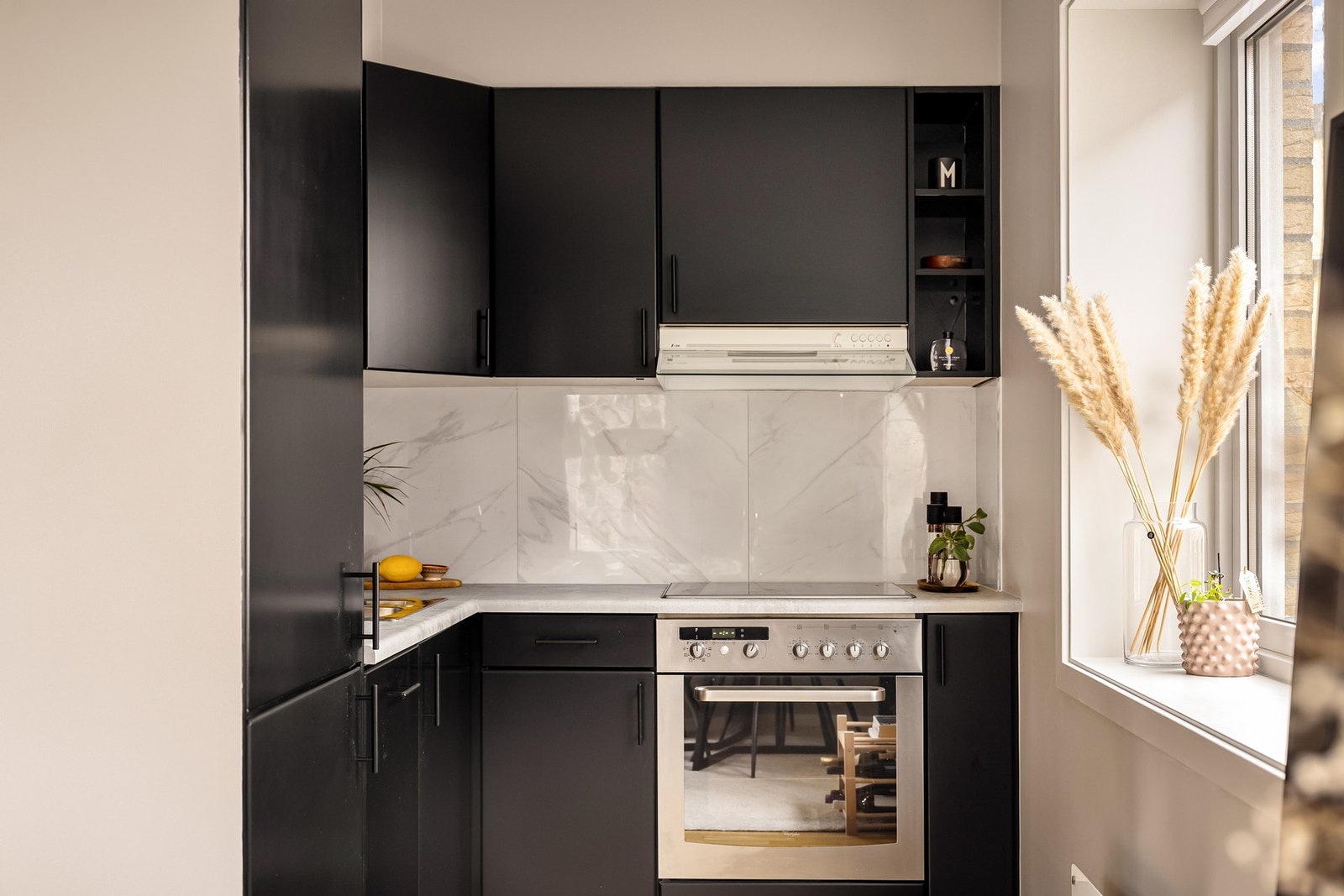 Pent kjøkken innredet med folierte, slette fronter og overskap med integrert benkebelysning. Galleribilde