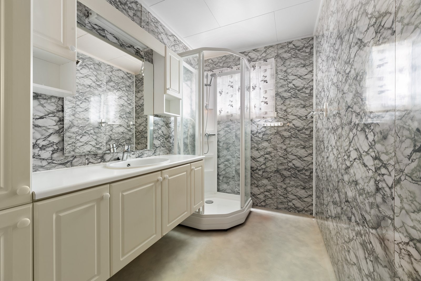 Bad med dusjkabinett og baderomsinnredning som har rikelig med skapplass. I boligen er det et lite toalettrom med servant som har dør fra yttergang. Baderomsplater på veggene. Våtromsgulv med gulvvarme. Galleribilde