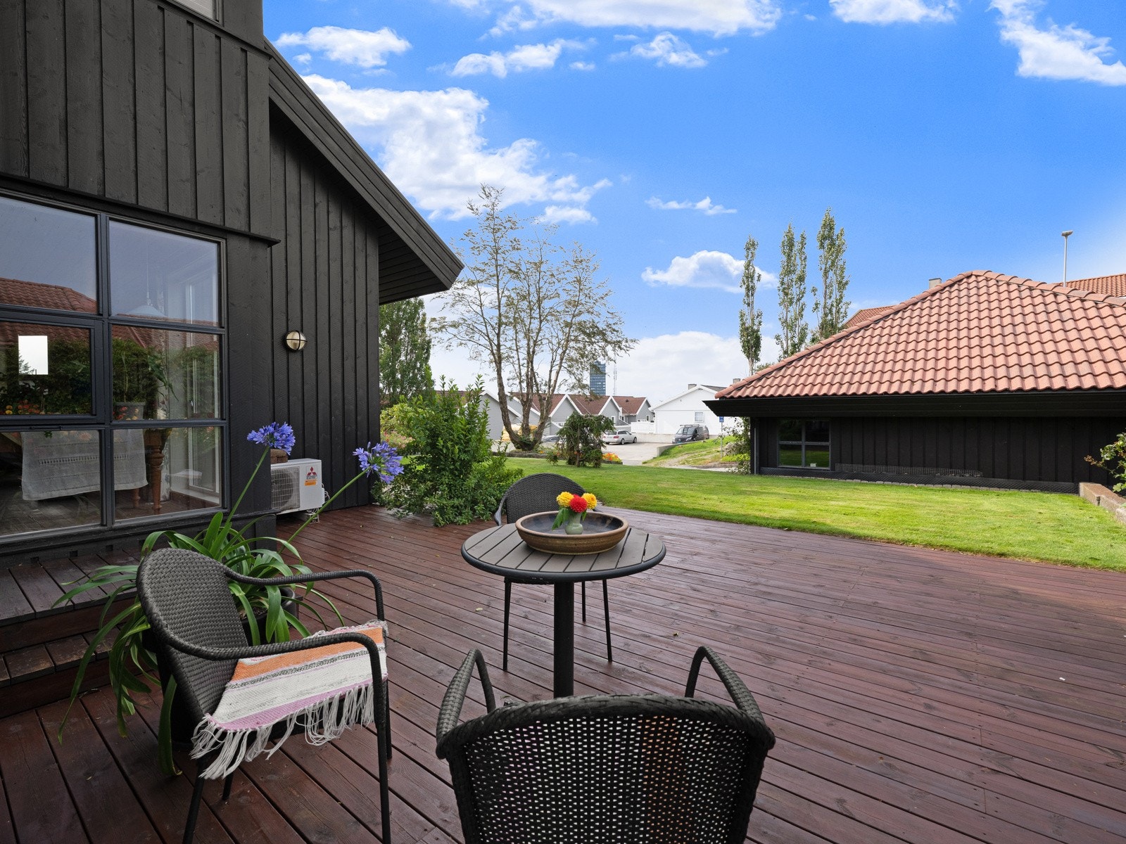 Terrassen strekker seg rundt deler av boligen og gir mulighet for å flytte på seg og følge solen i løpet av dagen. Galleribilde