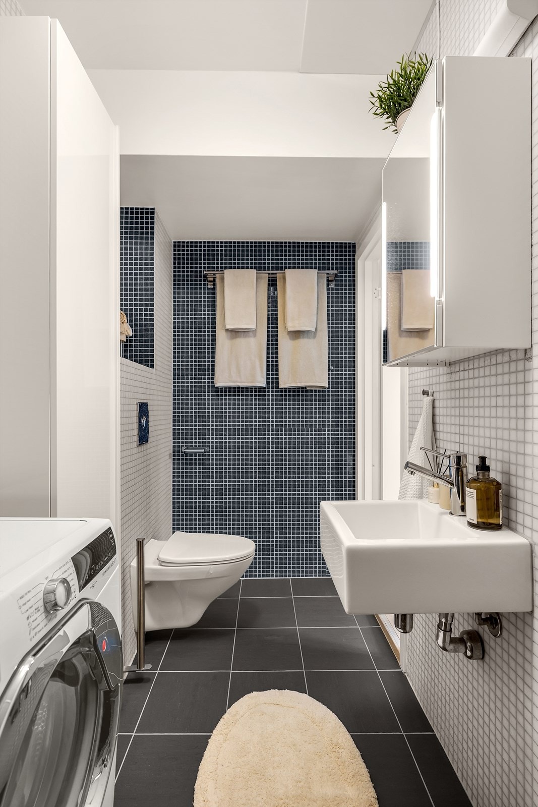 Badet er utstyrt med vegghengt toalett, servant, speilskap, dusjhjørne og har opplegg for vaskemaskin. Galleribilde