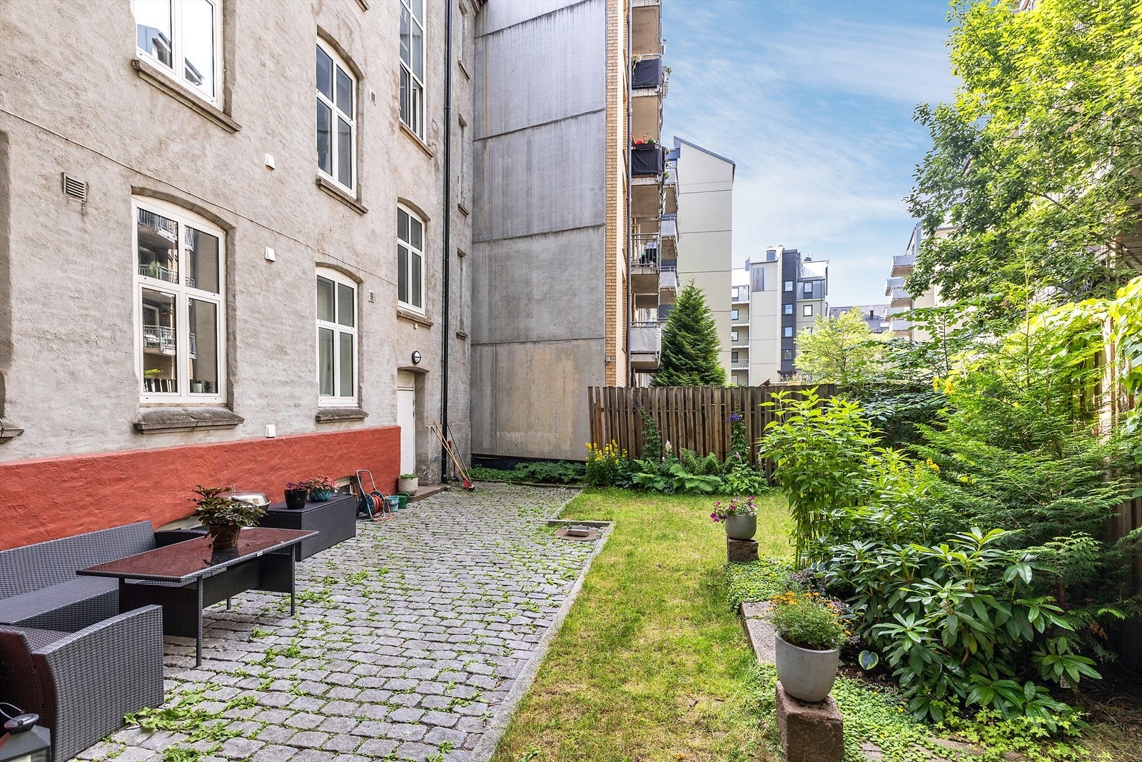 Hyggelig bakgård med beplantning, plen og sittegruppe. Galleribilde