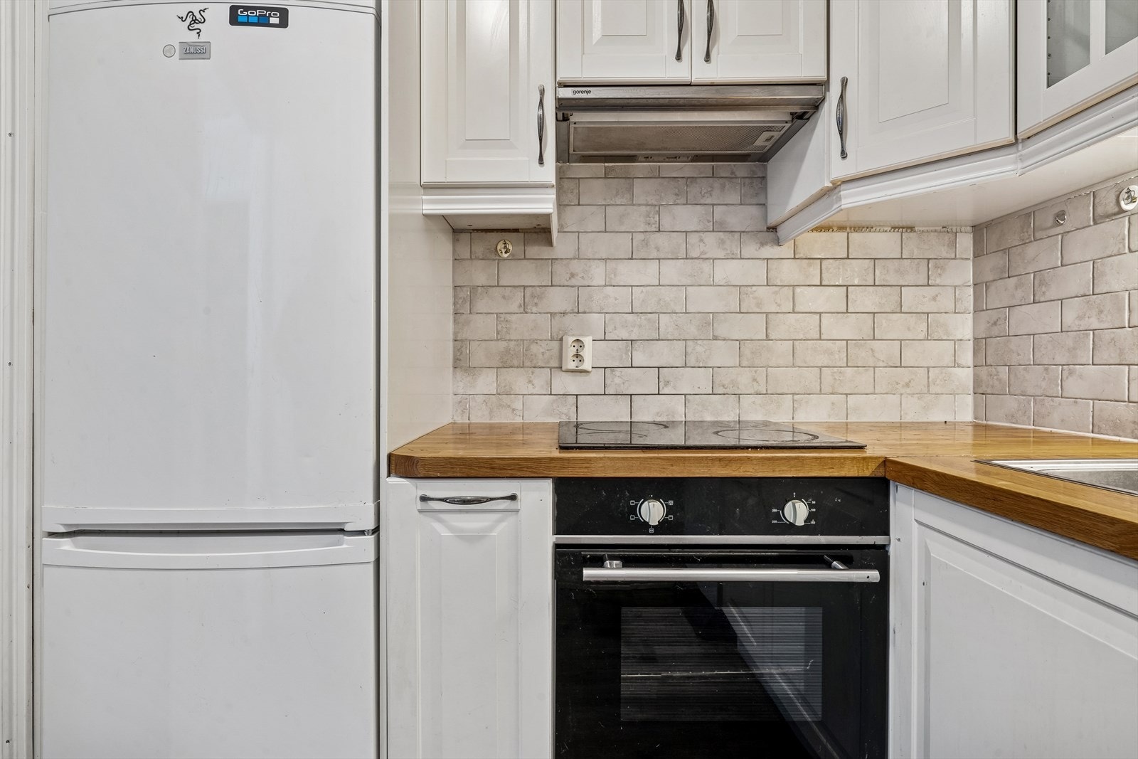 Fliser over kjøkkenbenk. Integrert platetopp og stekeovn. Galleribilde