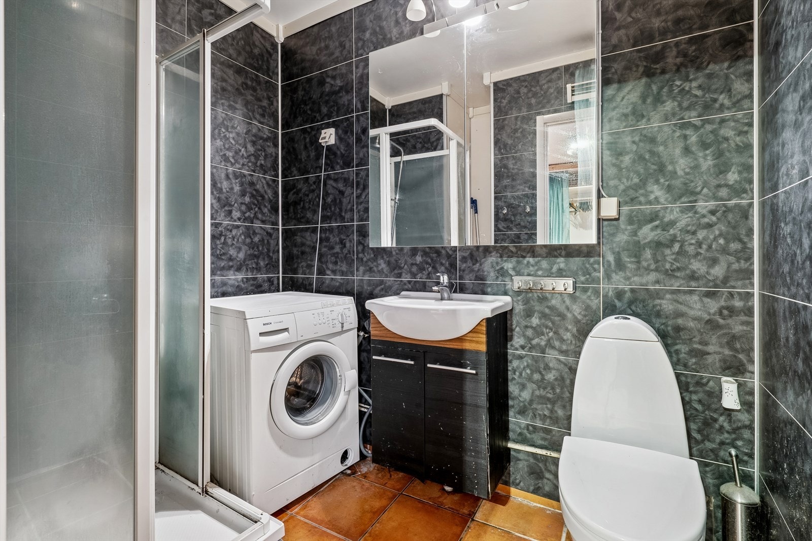 Flislagt bad med dusjkabinett og opplegg for vaskemaskin. Galleribilde