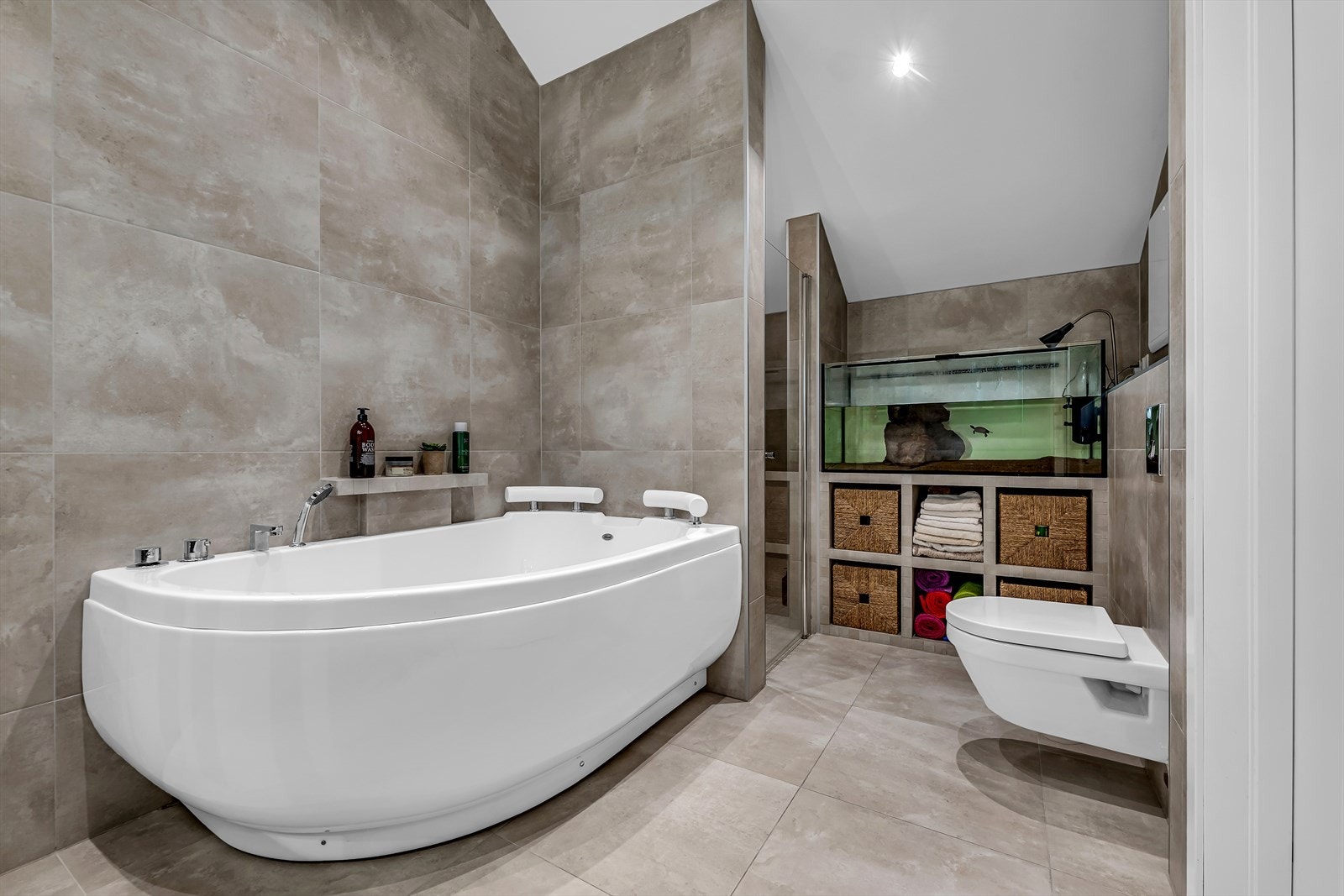 Lekkert flislagt bad. Rommet har gulvvarme og er innredet med to dusjer (regndusj) i egen nisje, dobbelt servant fra Villeroy & Boch med dimbar belysning og Tapwell waterfall servantbatteri, hjørnebadekar og vegghengt toalett. Galleribilde