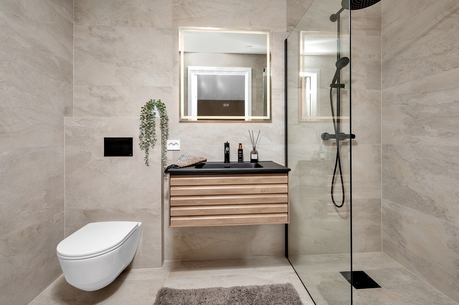 Eget baderom tilknyttet hovedsoverommet med vegghengt toalett, fin servant med oppbevaring og dusj Galleribilde