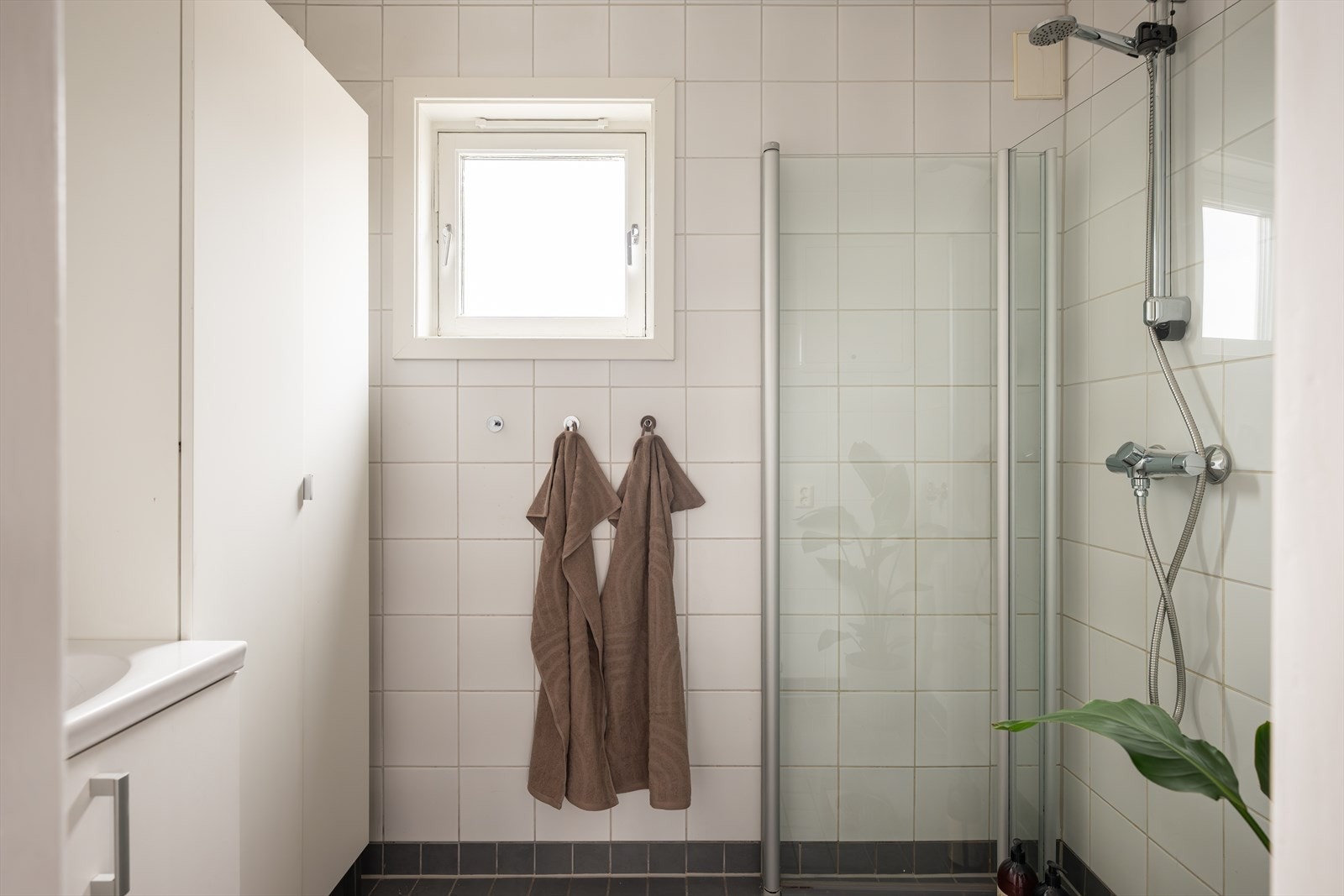 Videre er badet innredet med servantskap, innfellbare dusjdører, rørfordelingsskap og opplegg for vaskemaskin. Galleribilde