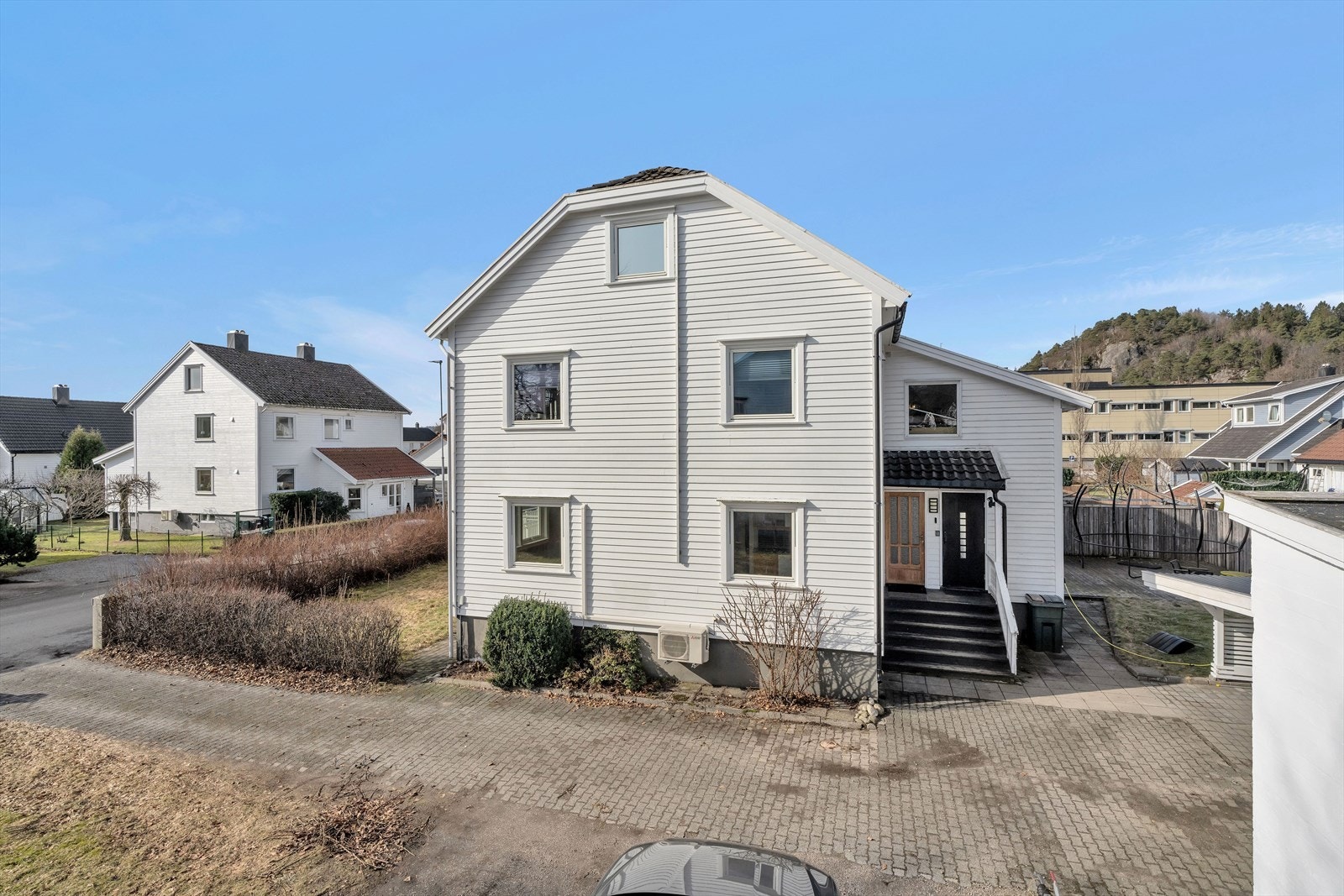 På baksiden av huset finner vi inngangsparti, samt bak boligen er det felles nedgang til kjeller som deles med del i 2. etasje. Galleribilde