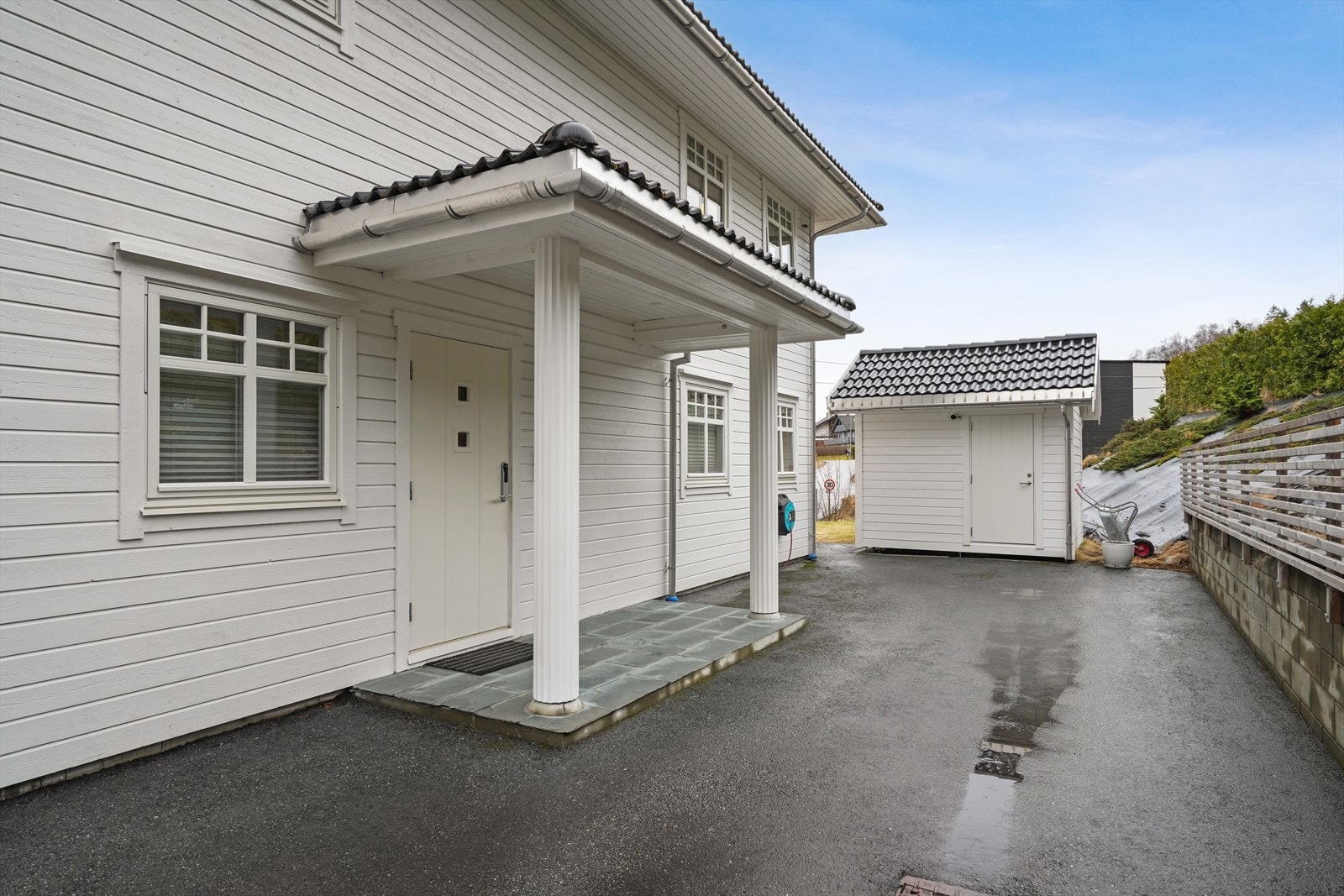 Overbygget inngangsparti med skiferheller ønsker velkommen inn. Galleribilde