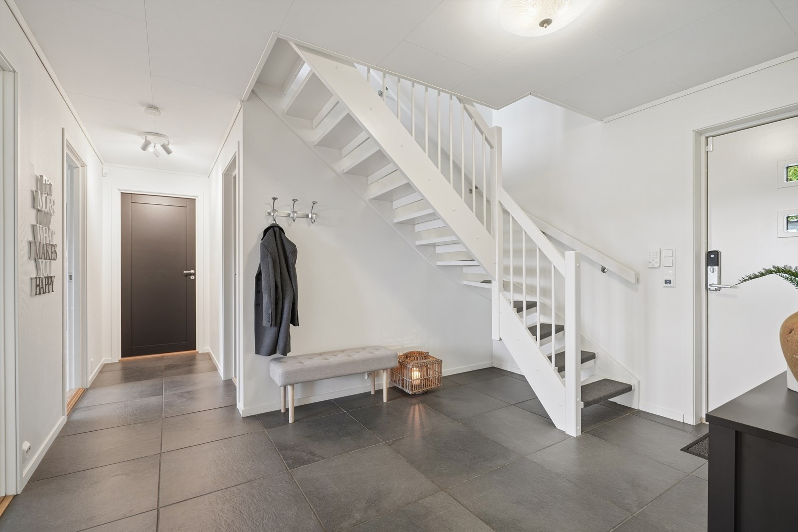 Romslig entré med store fliser på gulvet og trapp som leder opp til andre etasje. Galleribilde