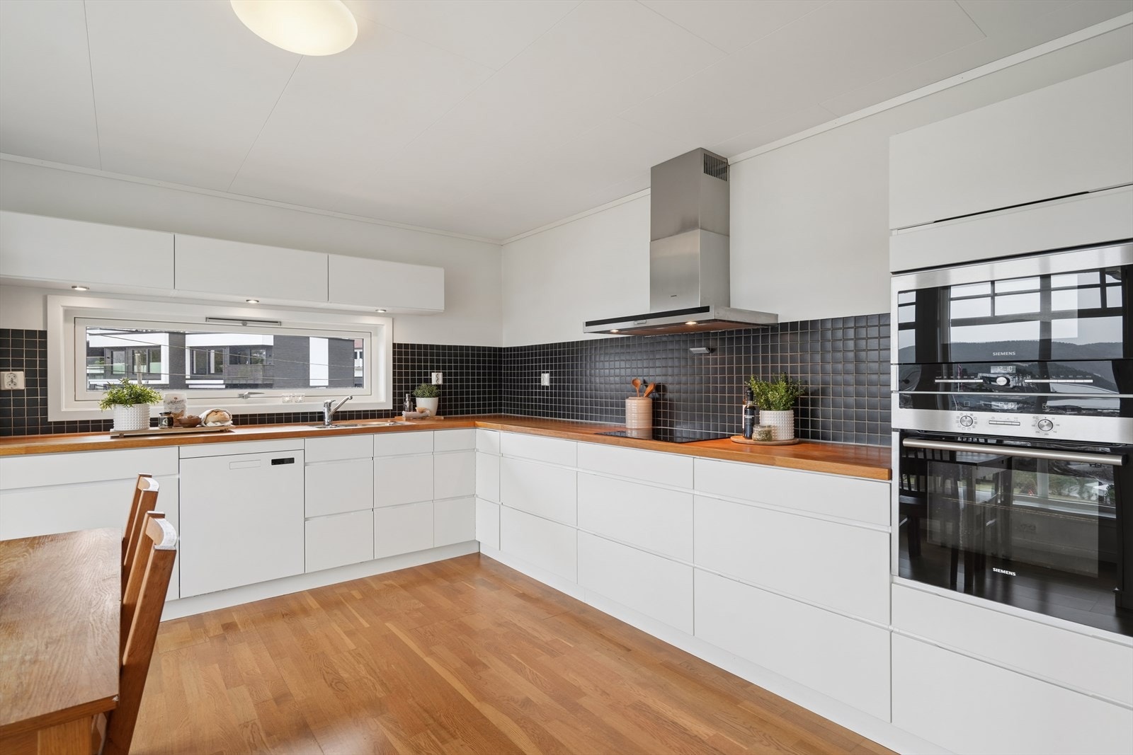 Stilrent kjøkken som har en funksjonell L-form med benkeplate i heltre eik og mørke fliser over benken. Galleribilde