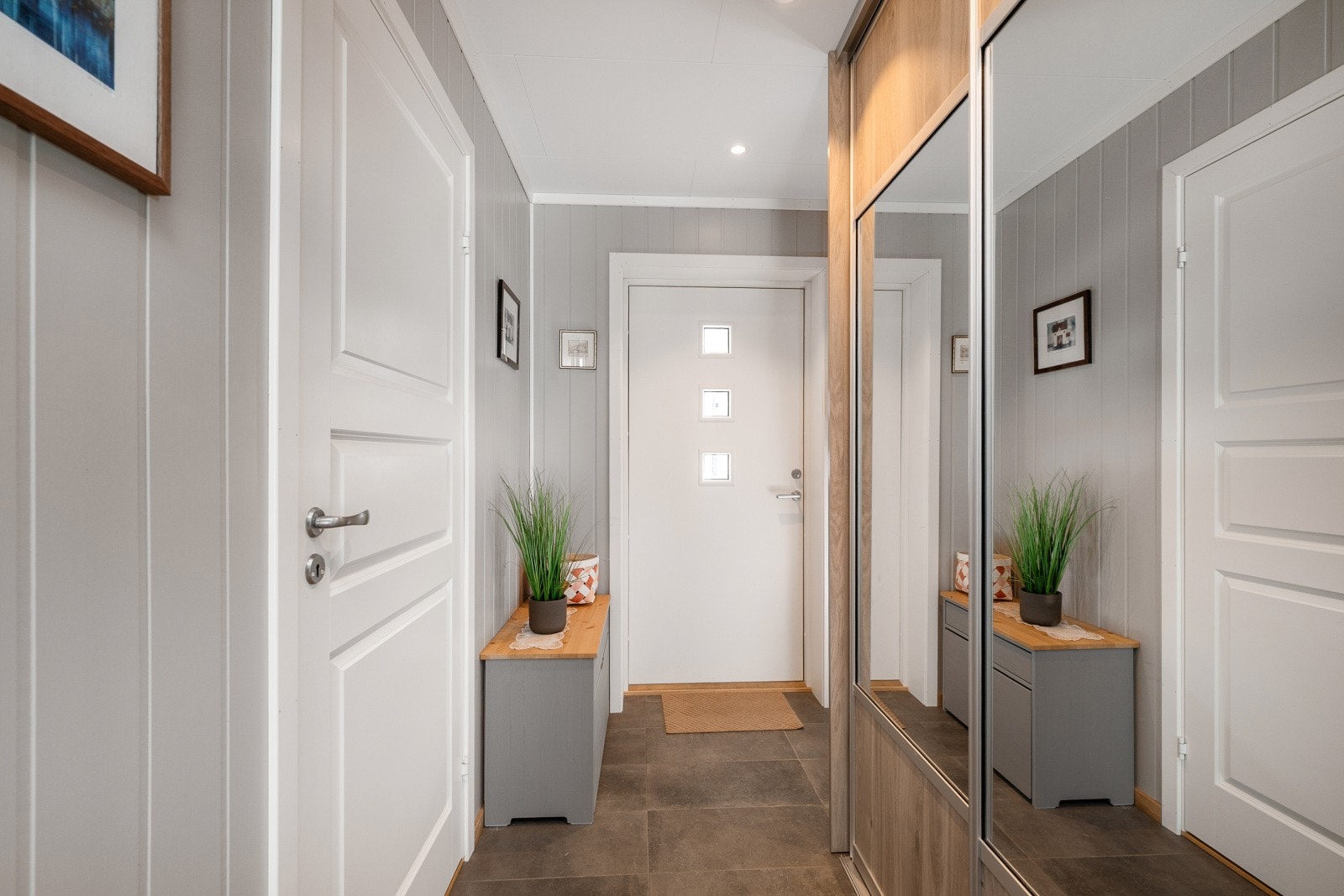 Entréen har flislagt gulv og god plass til oppbevaring, med tilgang til bad og en praktisk skyvedørsgarderobe. Galleribilde