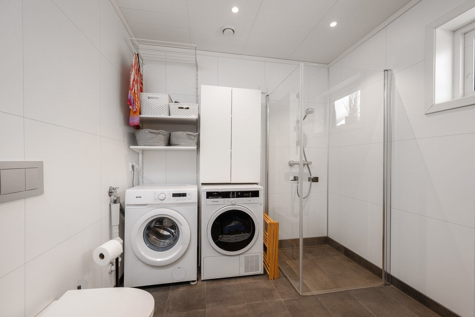 Rommet har servant med underskap, speil med belysning, dusjvegger og vegghengt toalett. Det er også opplegg for vaskemaskin. Galleribilde