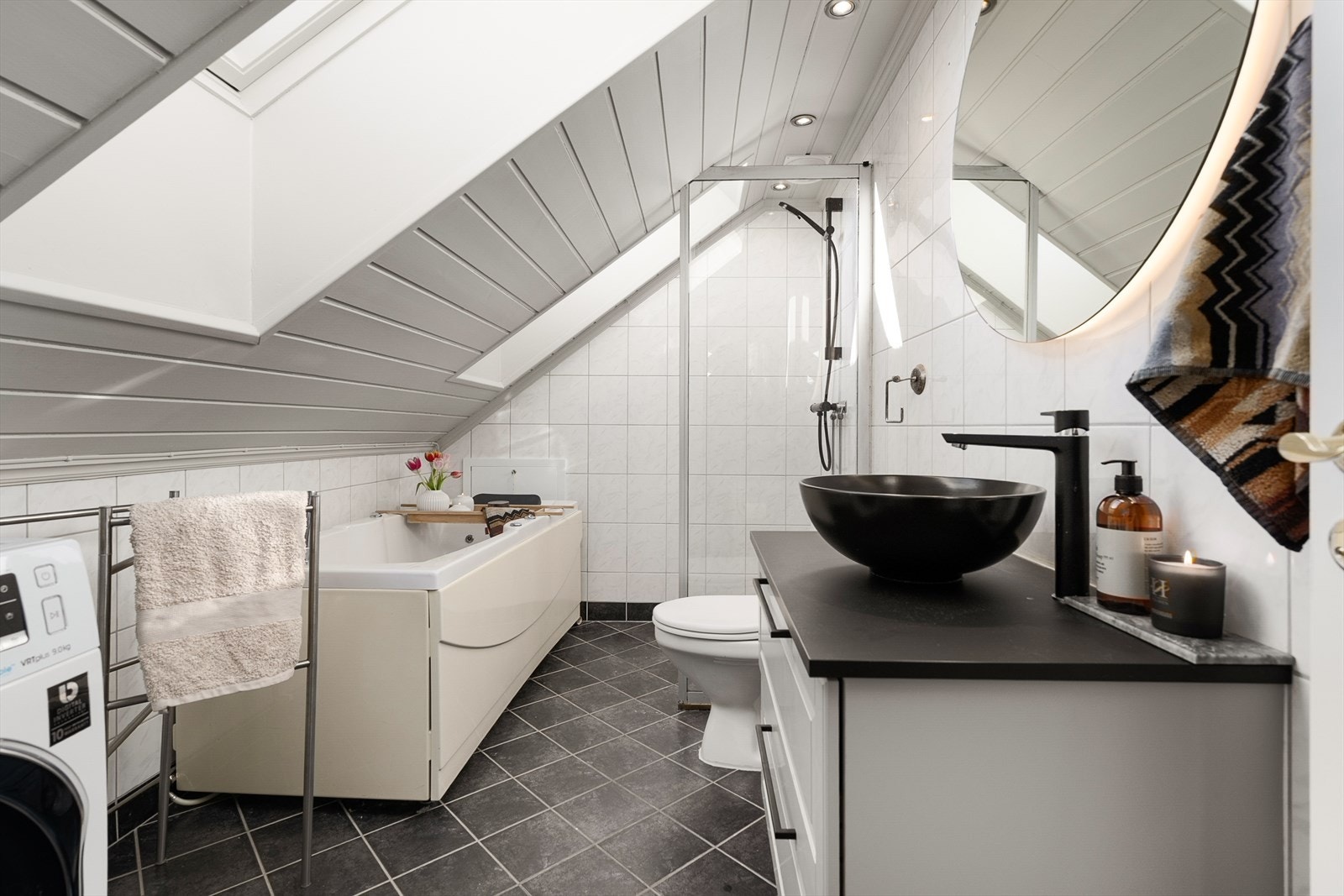 Badet er flislagt og utstyrt med både badekar og en praktisk dusjvegg i herdet glass. Galleribilde