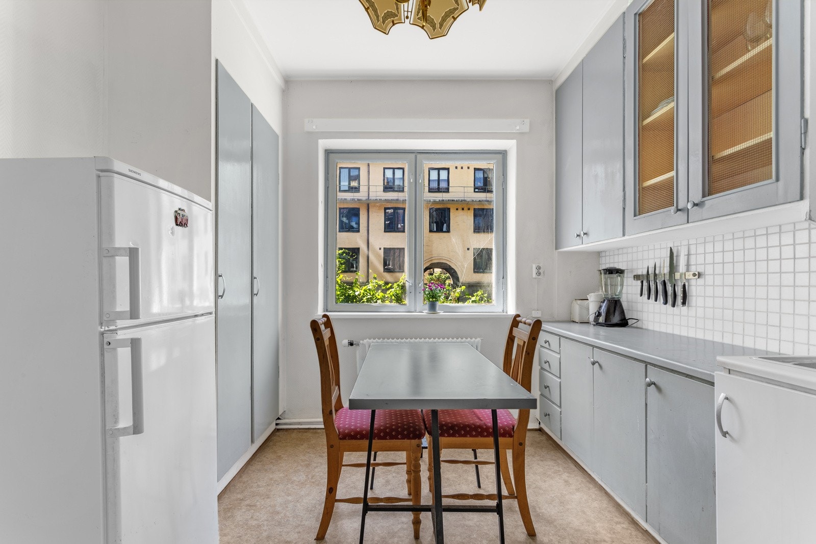 Eldre kjøkkeninnredning (ukjent år) med glatte, malte og folierte fronter. Benkeplate av laminat og fliser over benkeplaten sikrer enkel rengjøring etter matlaging. Galleribilde