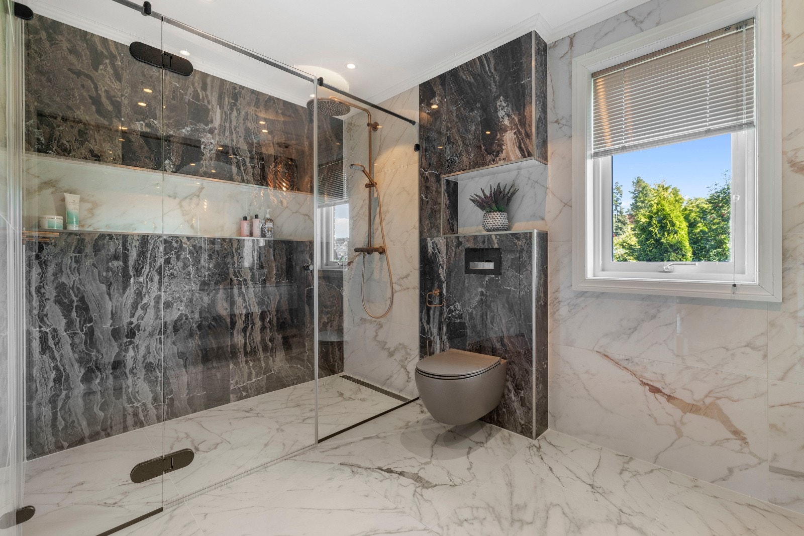 Badet har vegghengt toalett, rikelig med oppbevaringsplass og en flott servantløsning med stort, rundt speil over. Galleribilde