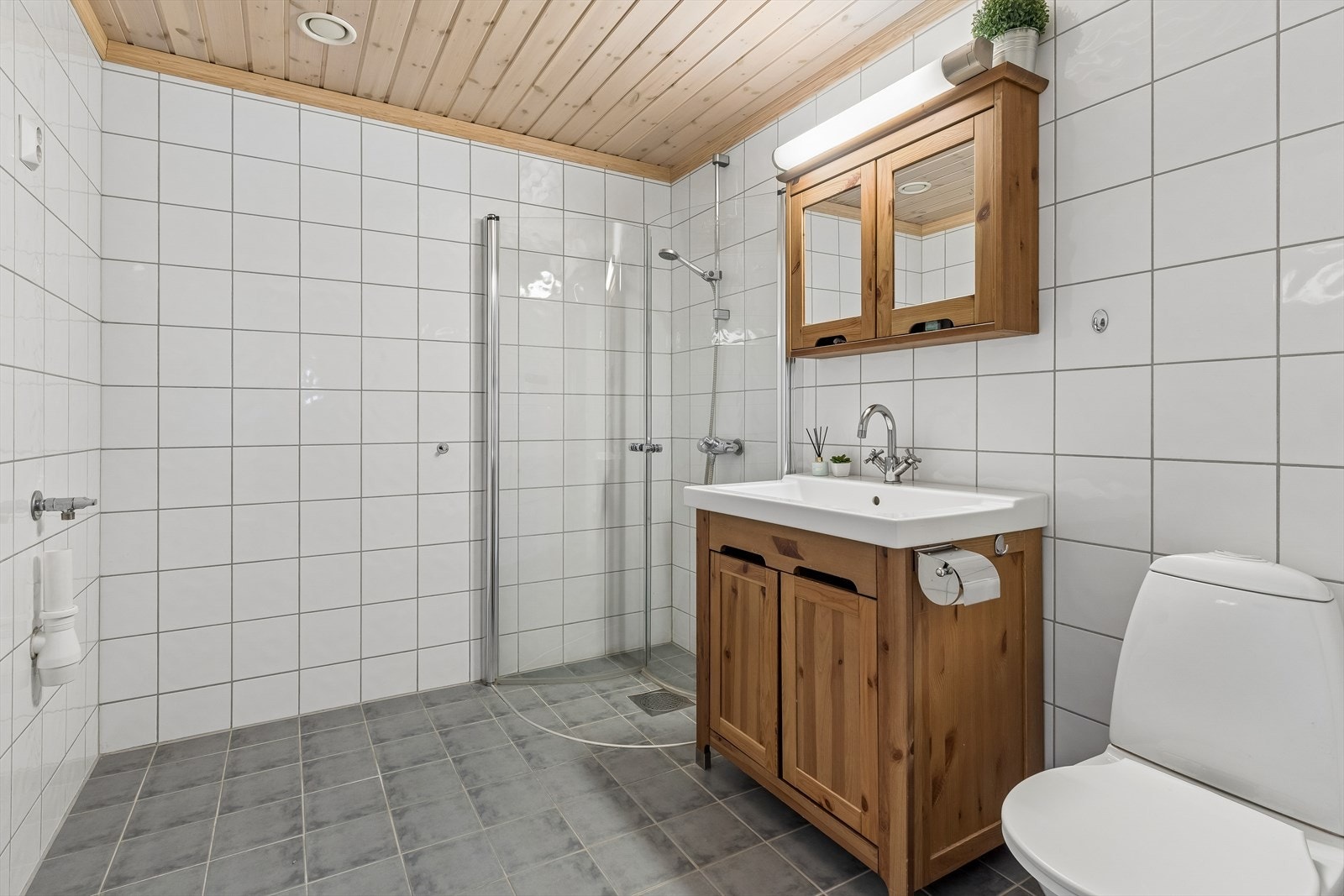 Flislagt bad med elektriske varmekabler i gulvet og opplegg for vaskemaskin. Galleribilde