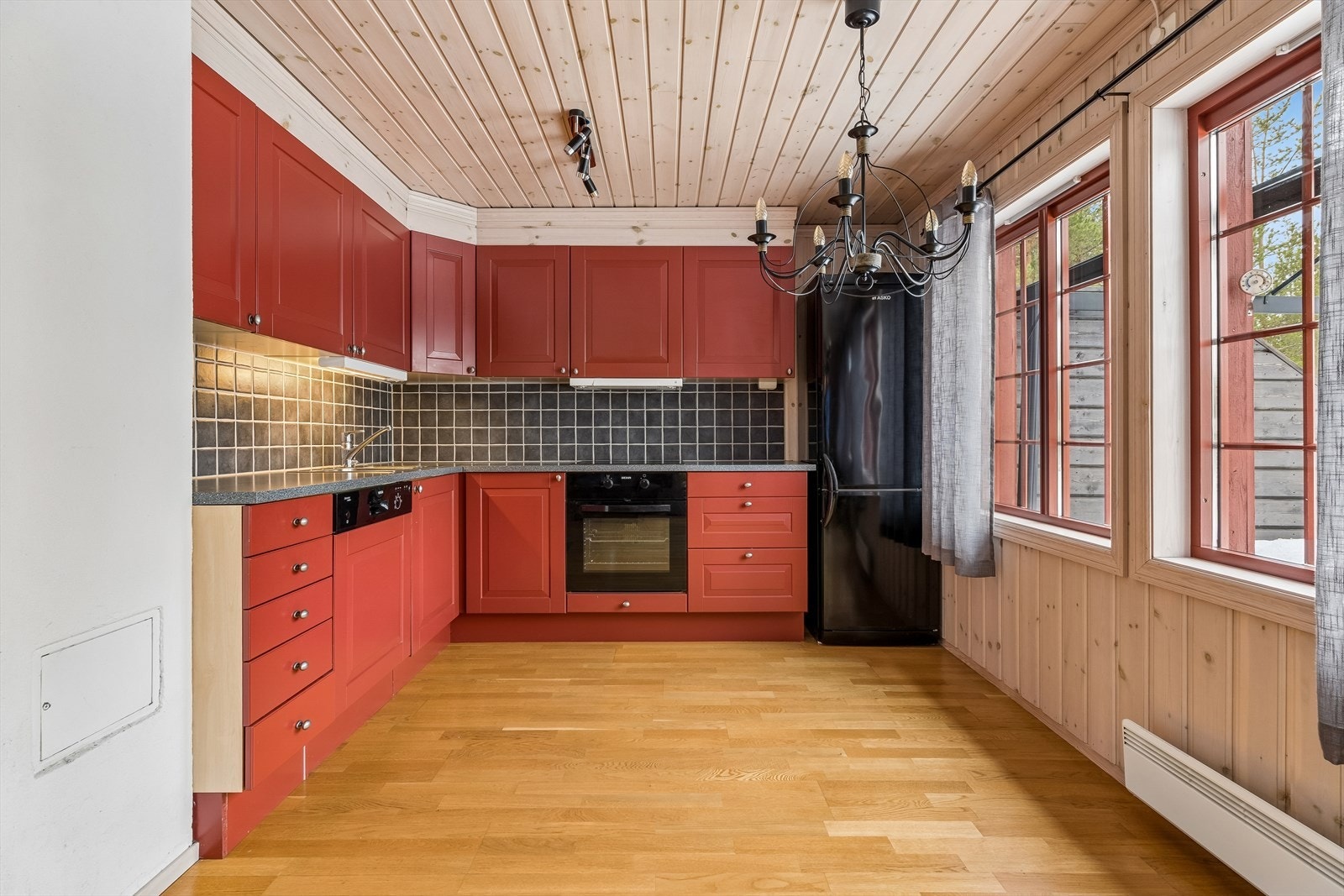 Kjøkkenet har en praktisk hjørneløsning med malte, profilerte fronter. Galleribilde