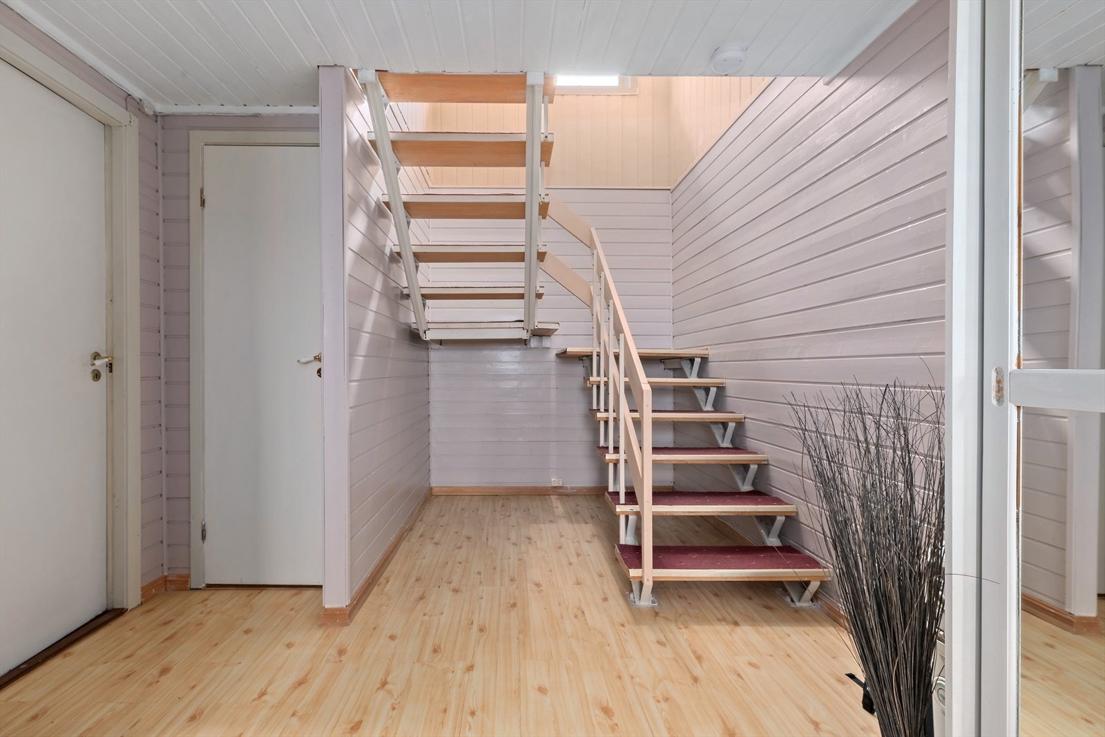 Romaslig hall. Trapp opp til hovedplan. Dør til gang som fører videre til 2 boder. Dør til toalettrom. Galleribilde