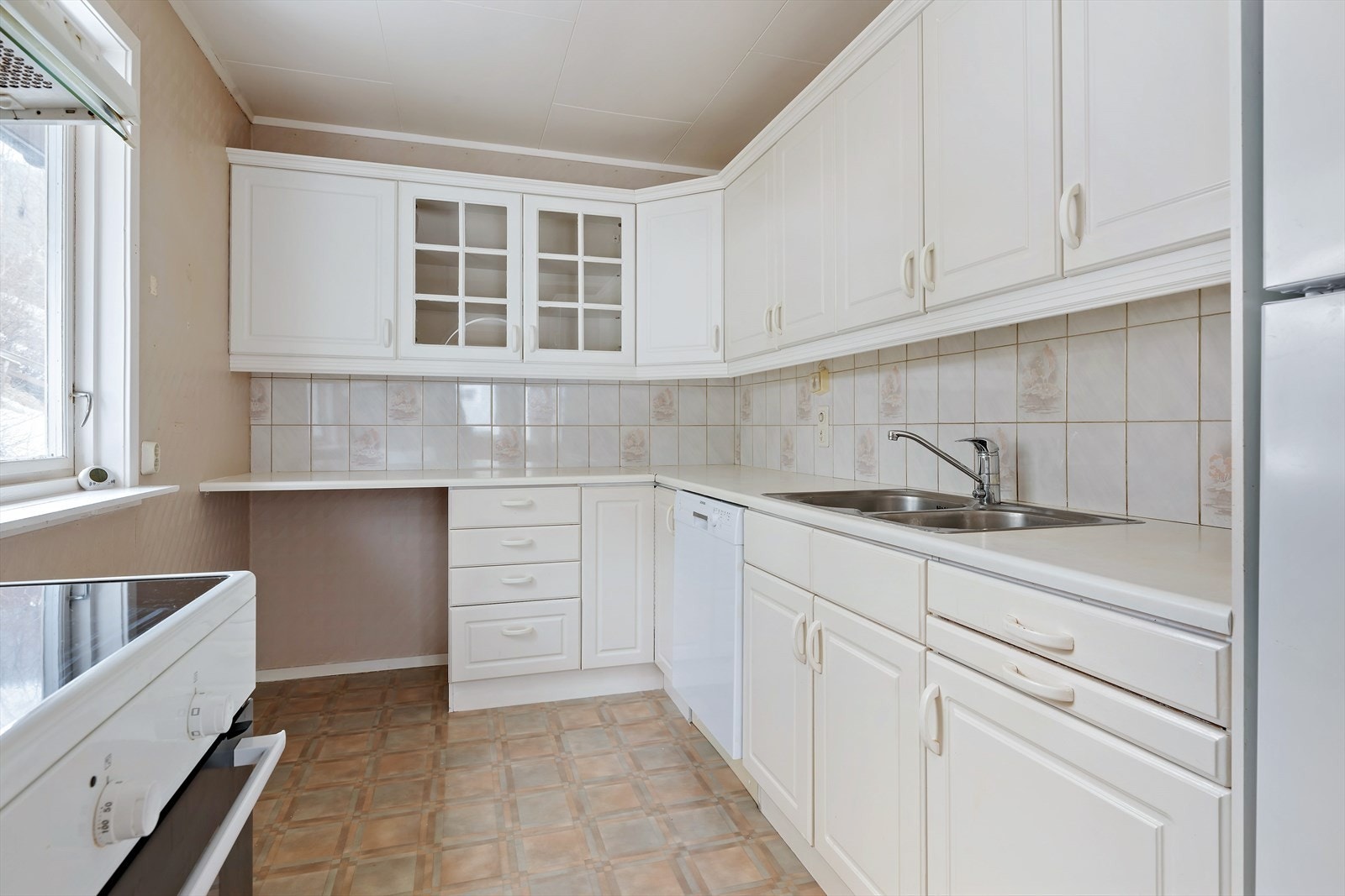 Kjøkkenet er lyst og trivelig. Hyggelig å kunne plassere et lite kjøkkenbord ved vinduet. Rikelig med skapplass. Hvitevarer som medfølger: komfyr, oppvaskmaskin og kjøleskap med liten fryser. Galleribilde