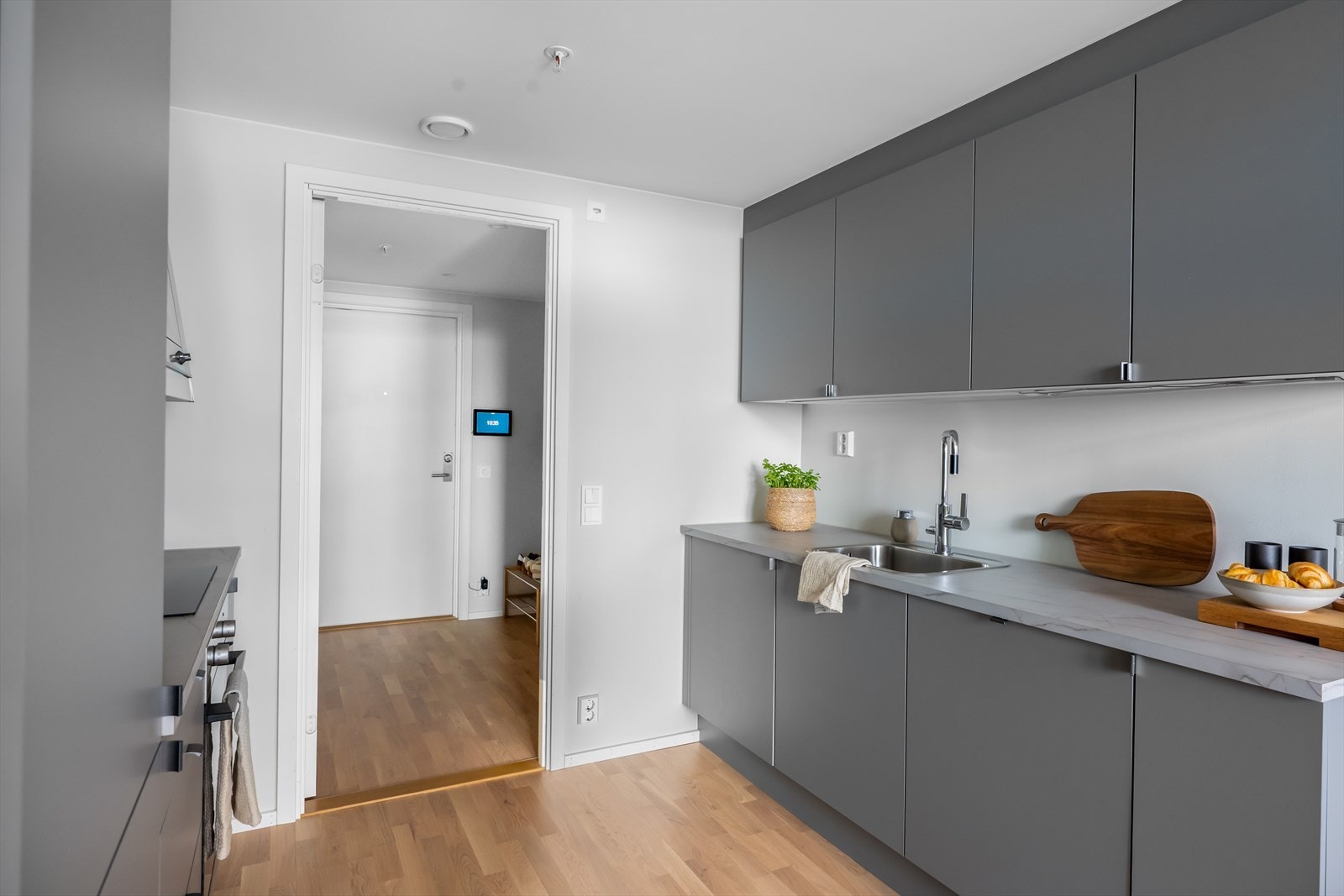 Moderne kjøkkeninnredning med glatte fronter og integrerte hvitevarer som platetopp, stekeovn, kjøleskap, fryser og oppvaskmaskin. Galleribilde