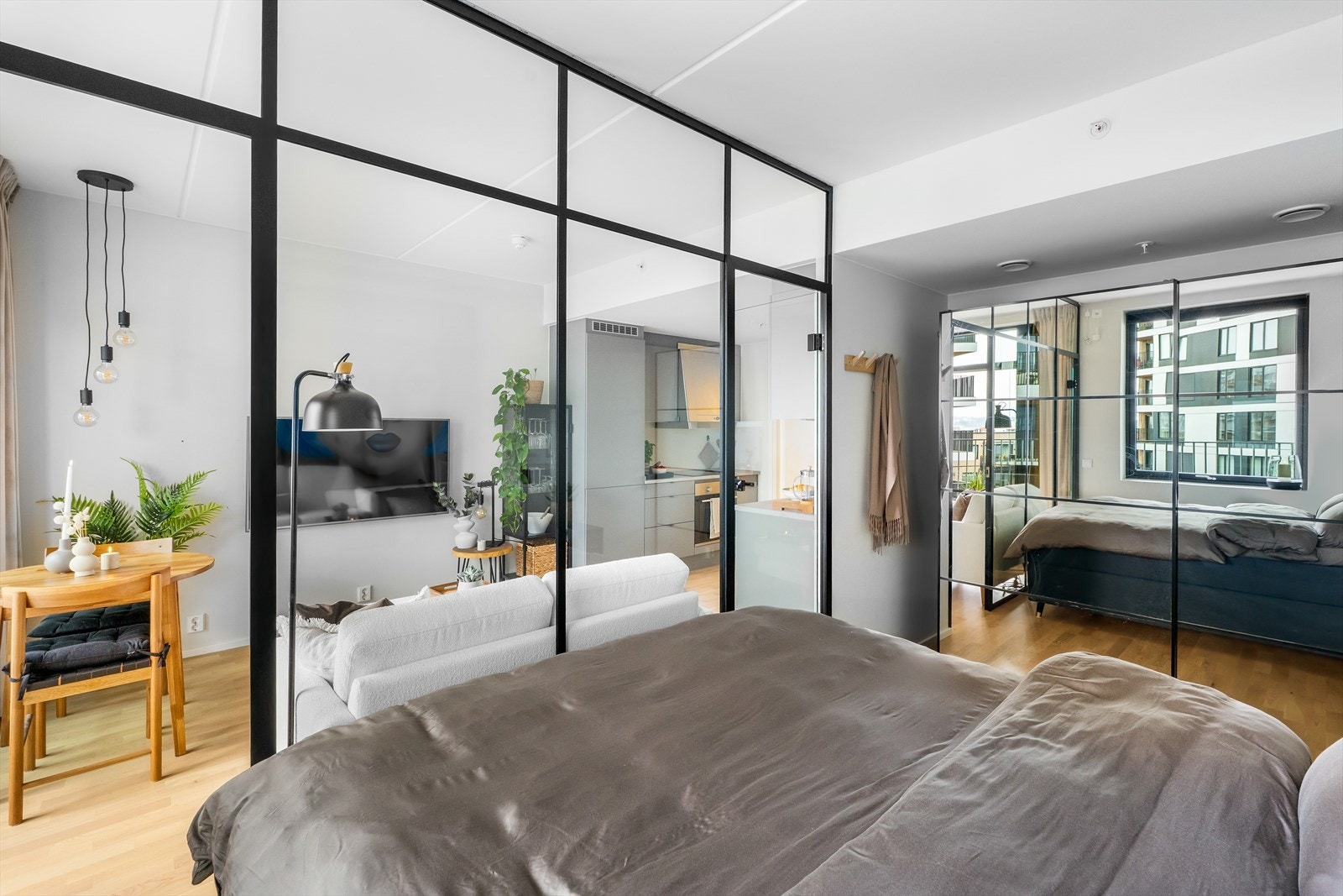 Stilfull glassvegg gir en forbindelse til resten av leiligheten og skaper en luftig atmosfære fra soverommet. Det er god plass til garderobeskap for oppbevaring. Galleribilde