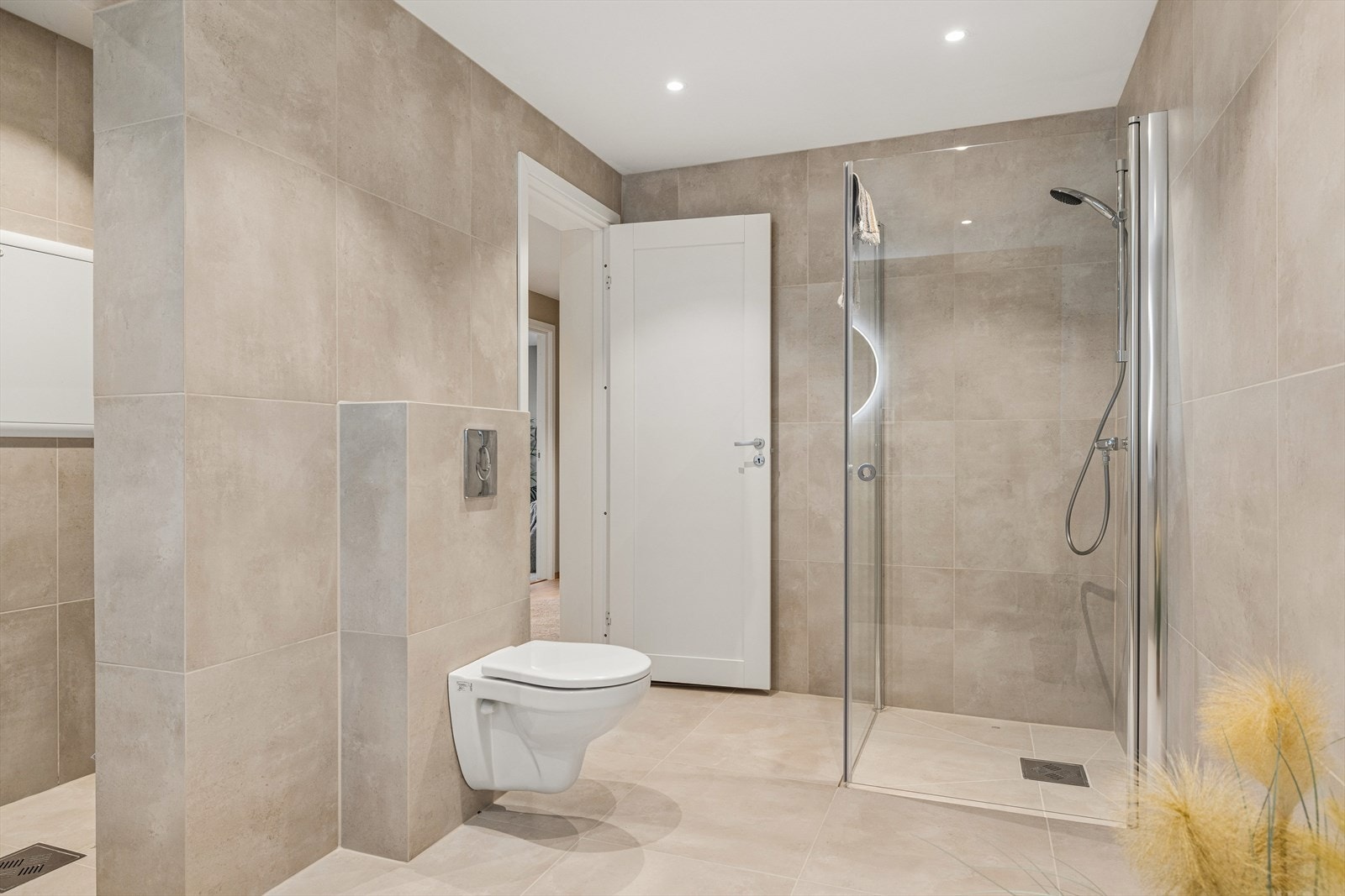 På badet er det dusjnisje med dusjdører, vegghengt toalett, samt innredning med arbeidsbenk og utslagsvask Galleribilde