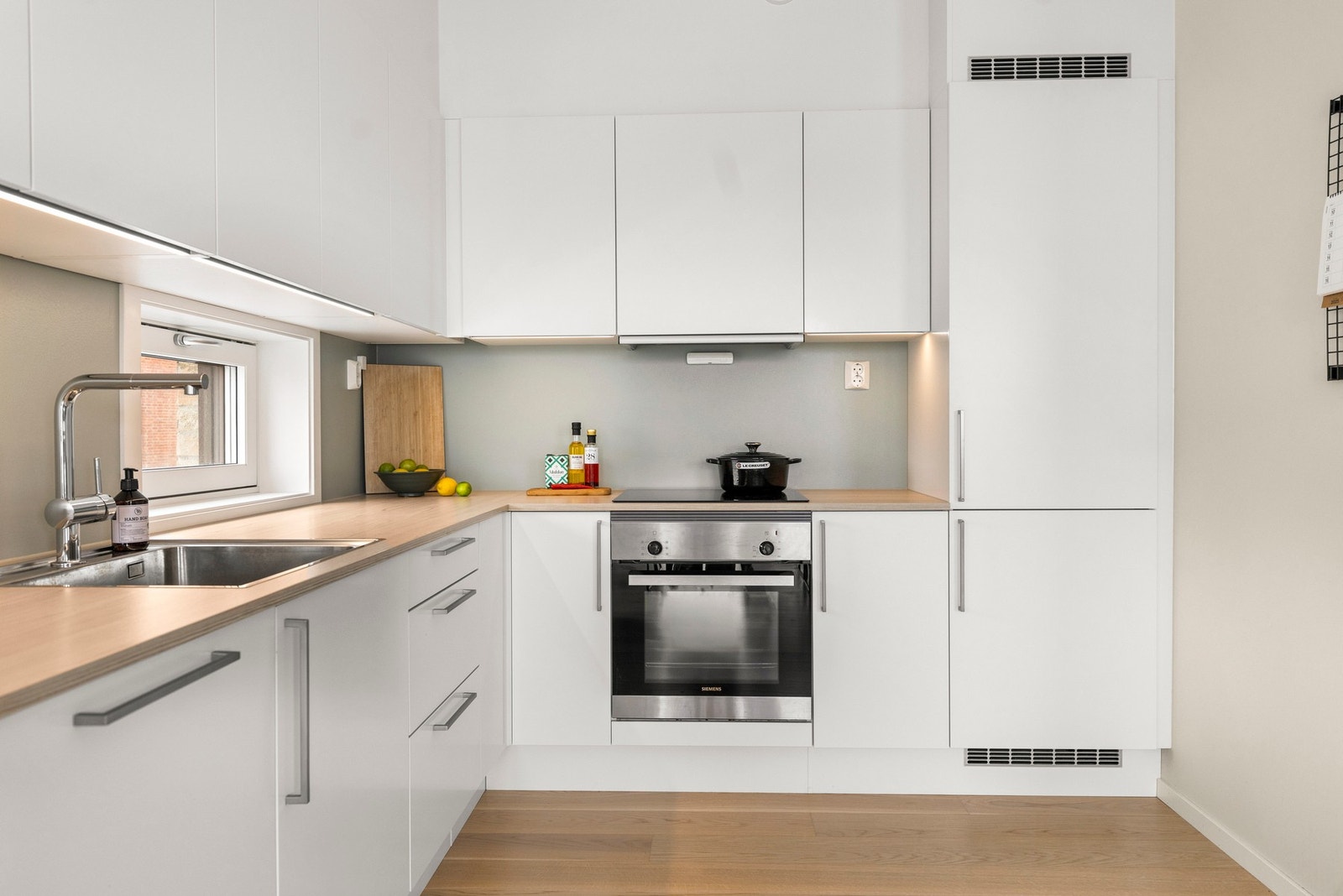 Benkeplaten er i laminat med nedfelt kum i rustfritt stål, og det er etablert belysning via LED-lyslist under overskap. Galleribilde