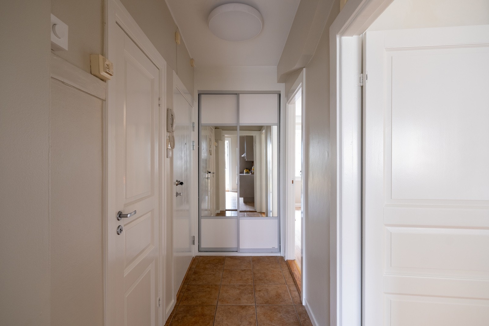 Lys entré med plass til yttertøy i garderobeskap. Fliser på gulv. Galleribilde