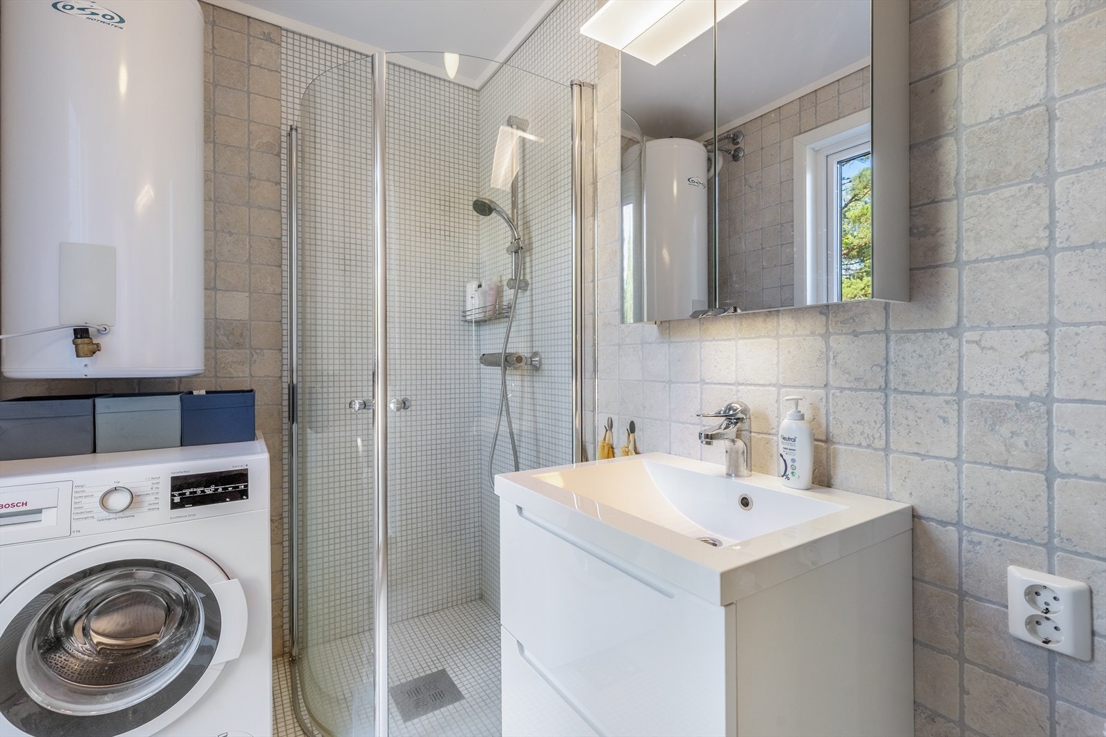 Badet er utstyrt med servant med underskap, speilskap over servant, dusjløsning og opplegg for vaskemaskin. Galleribilde