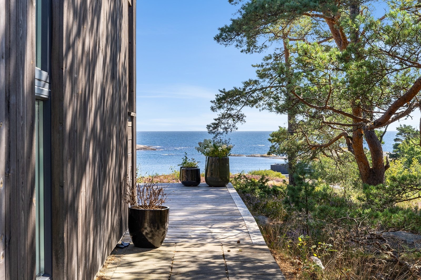 Gangsti langs fasaden leder videre mot utearealene. Galleribilde