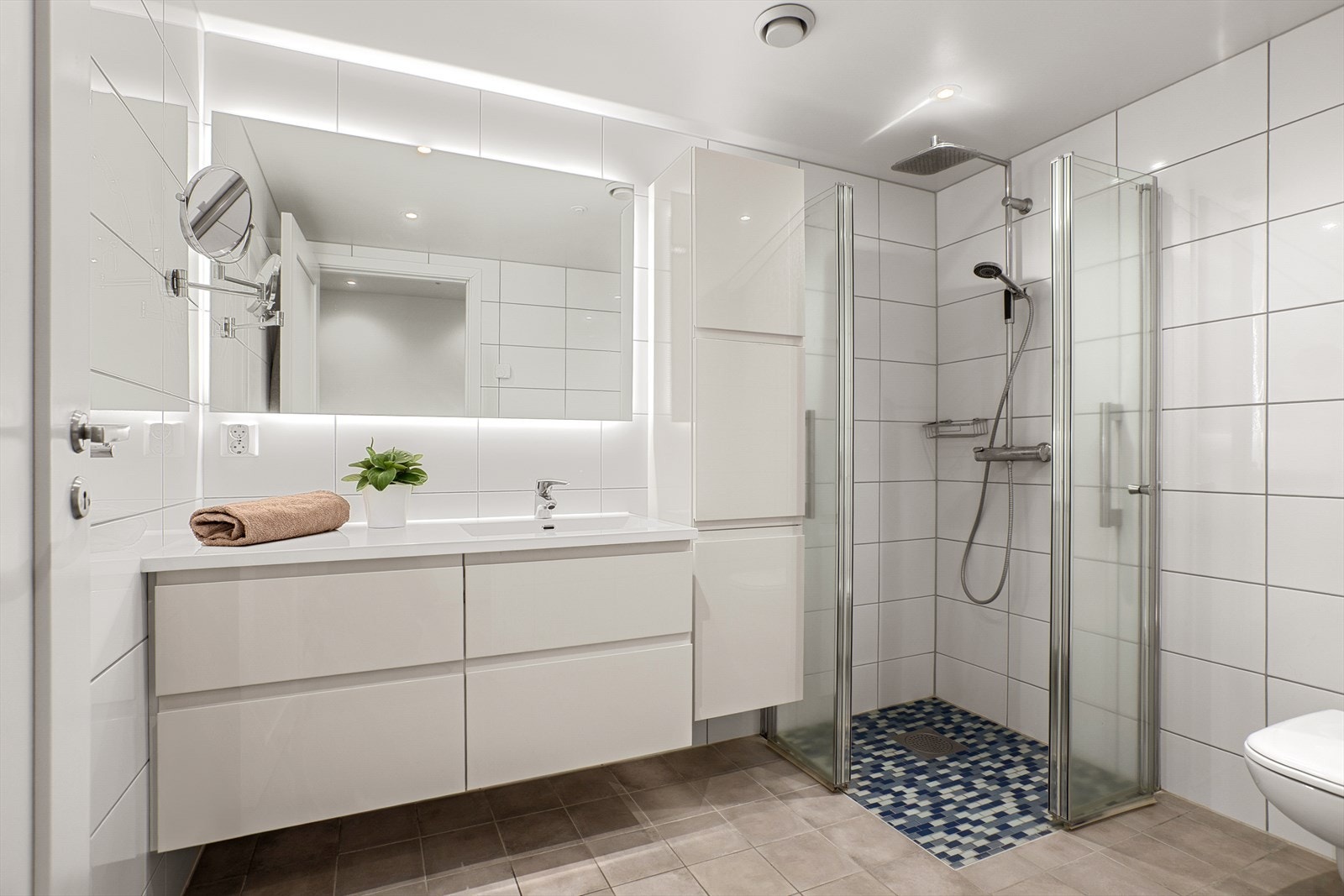 Leiligheten har et lyst og delikat helfliset bad med downlights i tak Galleribilde