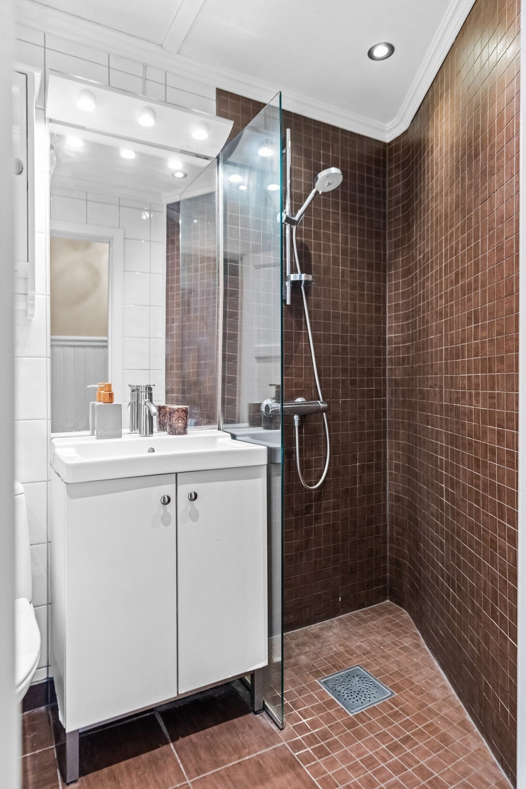 Flislagt bad med varmekabler i gulvet og praktisk dusjhjørne med glassvegg. Her er det også opplegg for vaskemaskin. Galleribilde