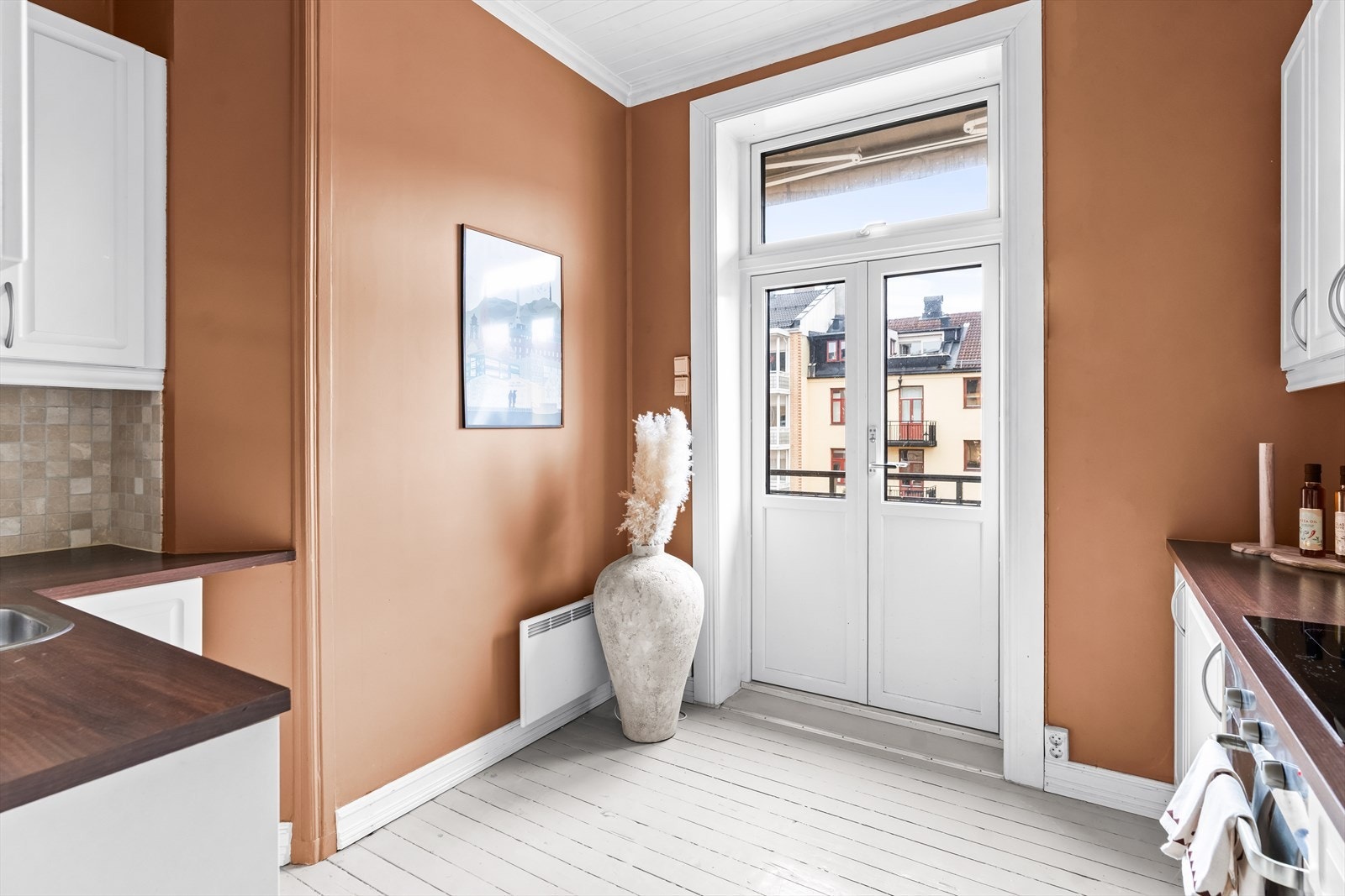 Lys og praktisk del av kjøkkenet med god plass til oppbevaring. Døren leder videre ut til balkongen. Galleribilde