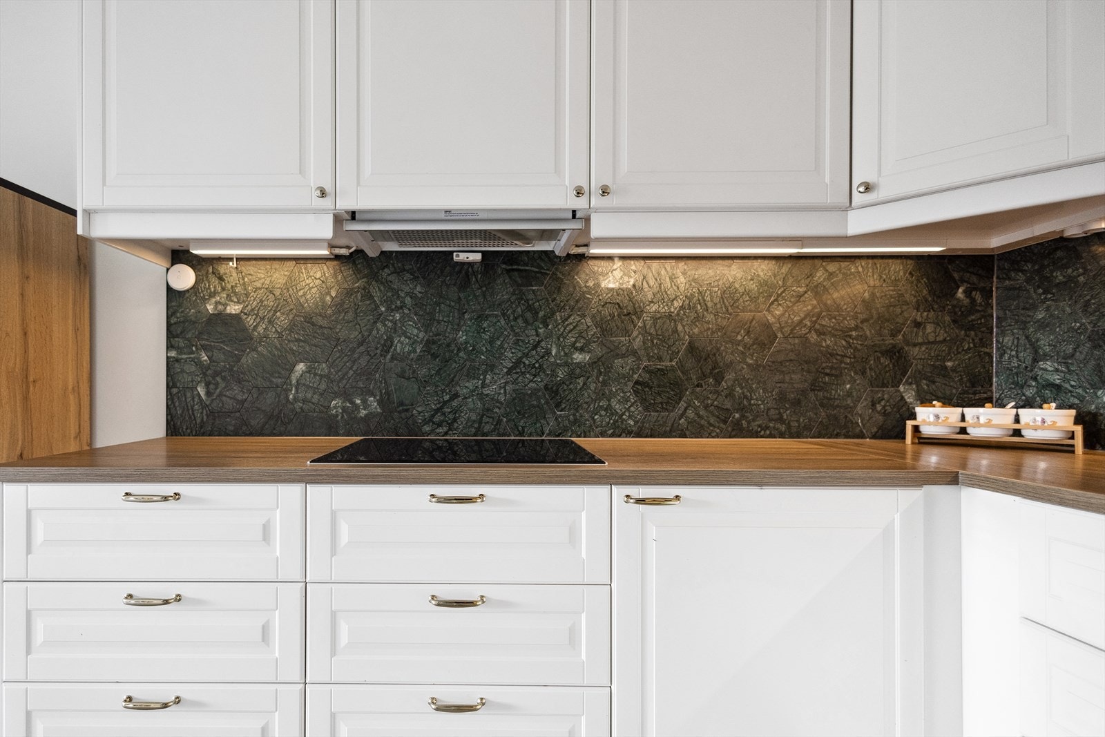 Innredningen har profilerte, fabrikklakkerte fronter og laminert benkeplate med kjøkkenkran og nedfelt kum i keramikk. Galleribilde