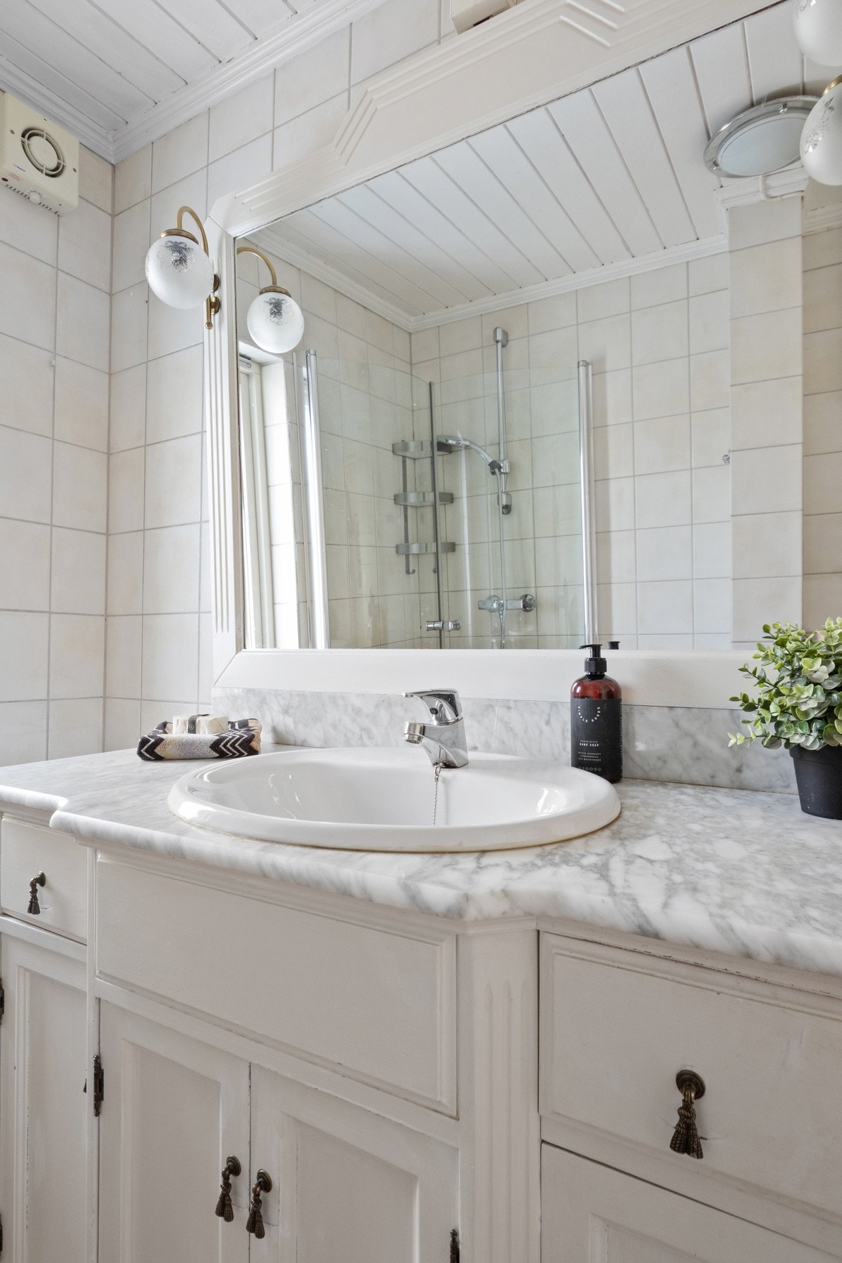 Baderomsinnredningen har hvite, profilerte fronter, marmorbenk og nedfelt servant Galleribilde