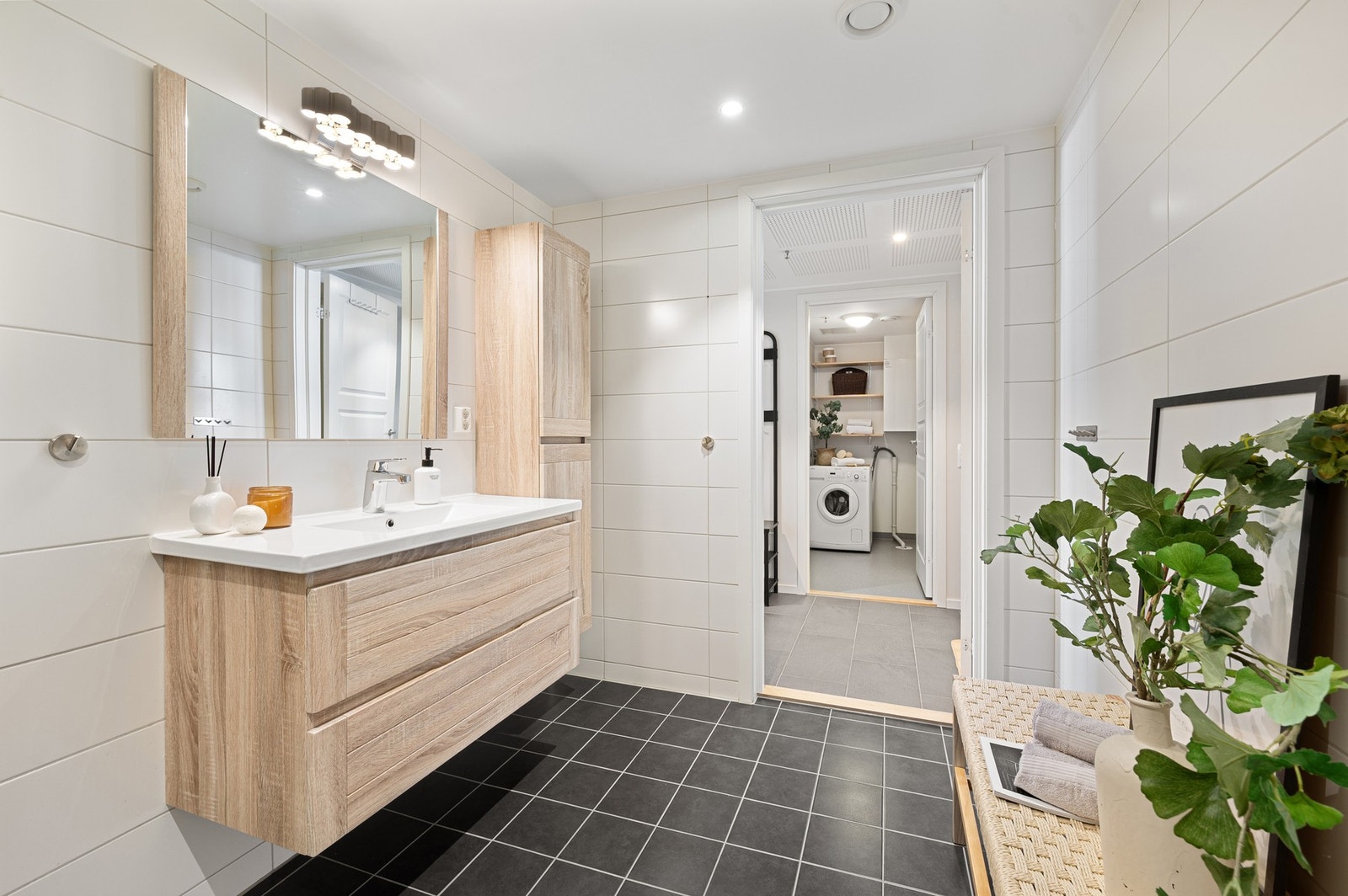 Badet er innredet med servantinnredning, sideskap, veggmontert toalett og dusjhjørne. Galleribilde