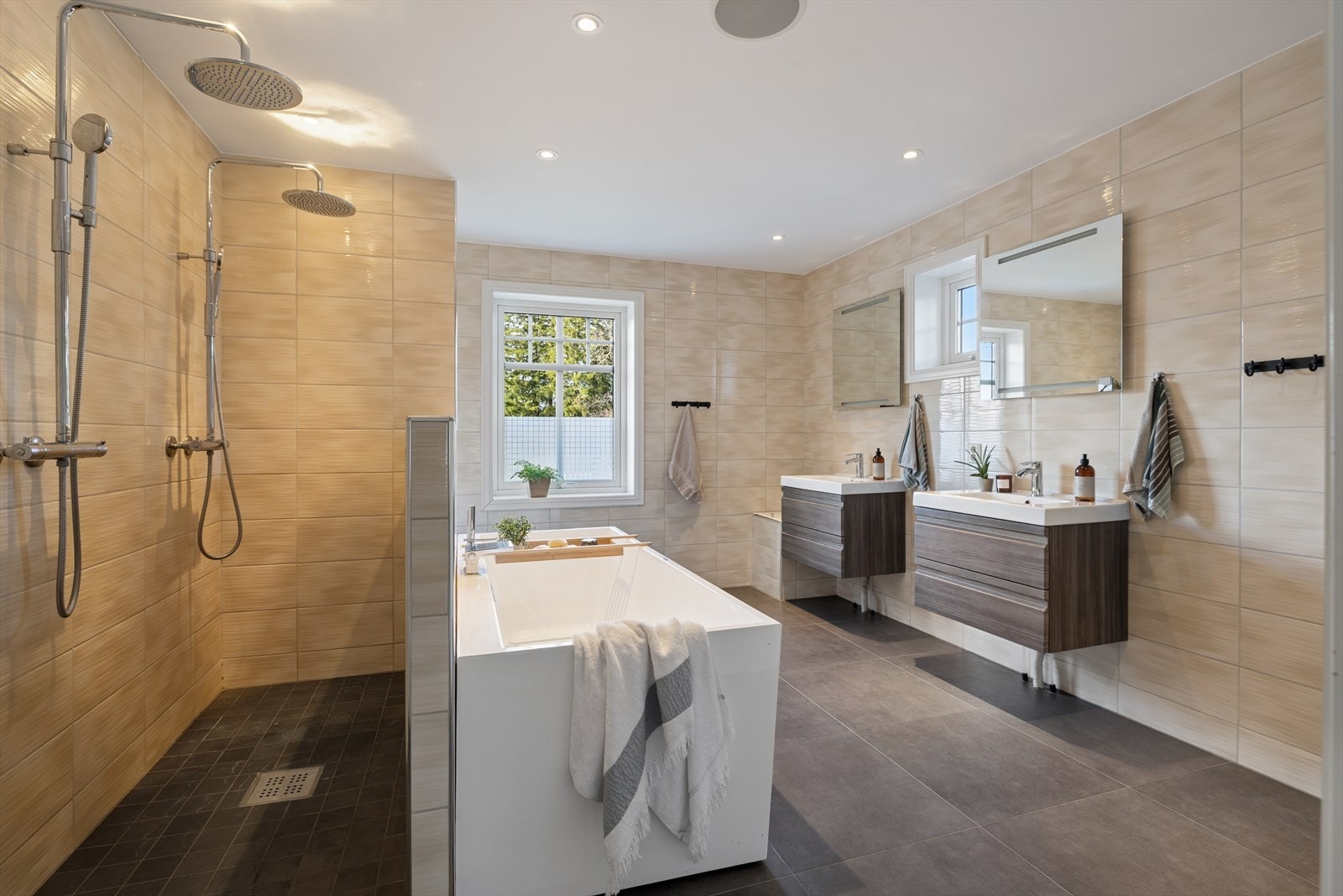 Flislagt bad i 2. etasje har gulvarme, vegghengt toalett, badekar, dobbeldusj i nisje og baderomsinnredning med servant. Praktisk klessjakt til vaskerom. Galleribilde