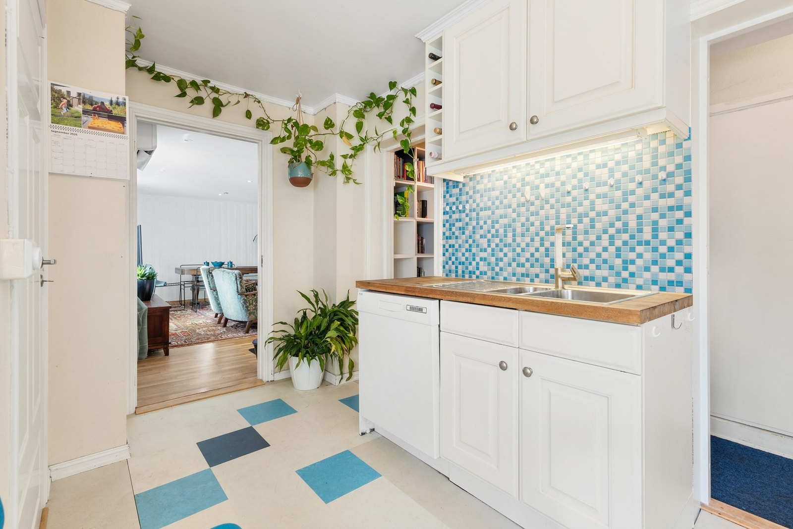 Kjøkken med hvite, profilerte fronter, trebenk og blå mosaikkfliser. Galleribilde
