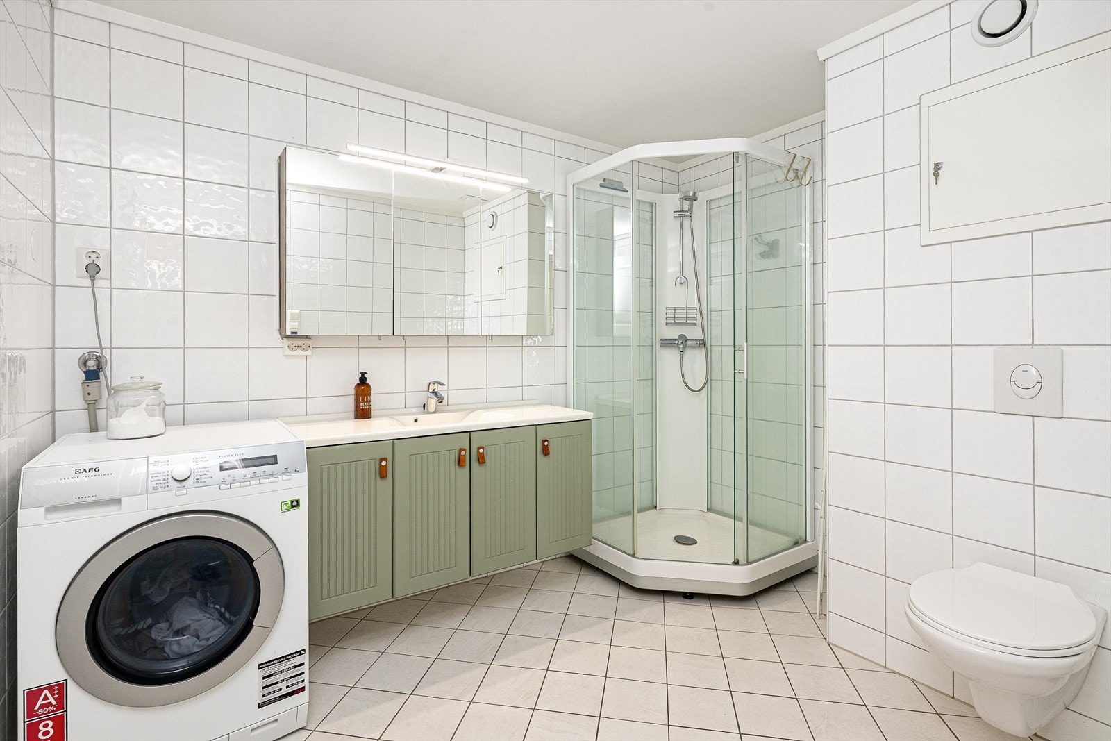 Flislagt bad fra 2016 med gulvvarme og opplegg for vaskemaskin. Badet er ellers innredet med vegghengt toalett, dusjkabinett og servantinnredning med underskap, overskap med speildører og lys. Galleribilde