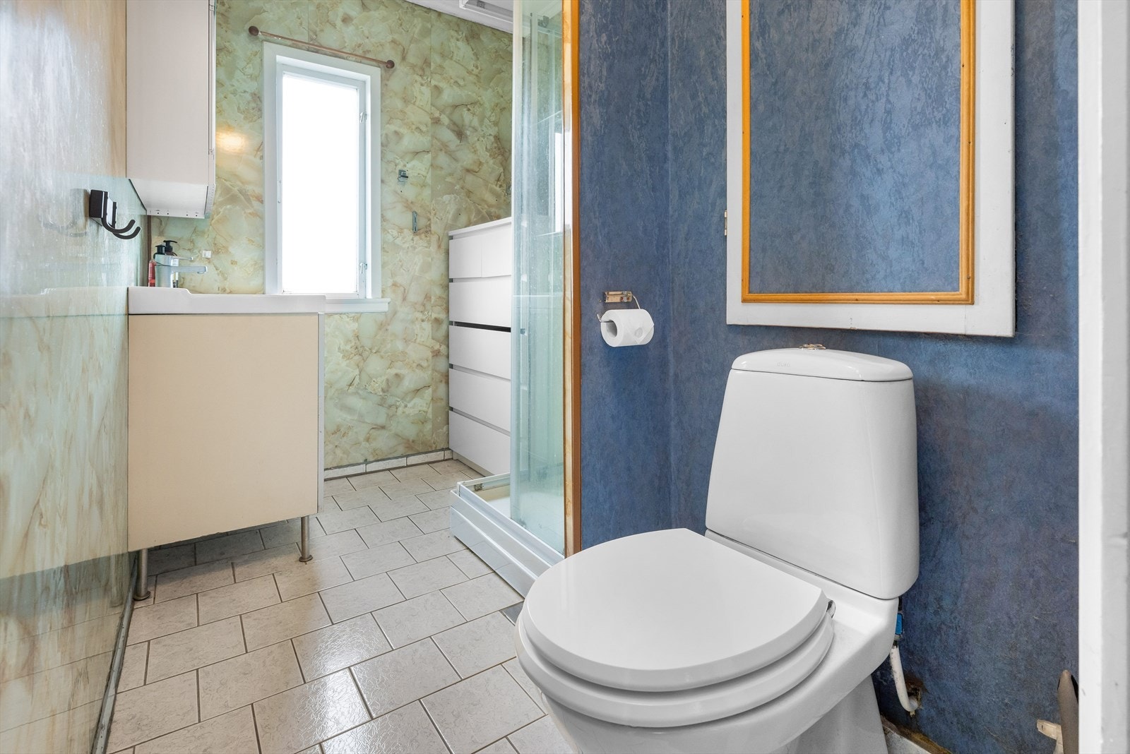 Baderommet er funksjonelt med fliser på gulvet og baderomspanel på veggene. Stor baderomsinnredning og praktisk dusjkabinett. Galleribilde