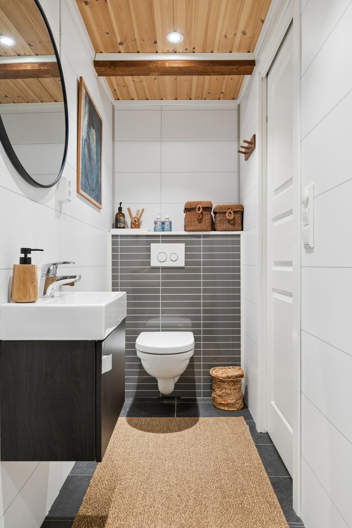 Badet er innredet med vegghengt servantskap med servant, dusjkabinett og vegghengt toalett med spalte for avrenning Galleribilde