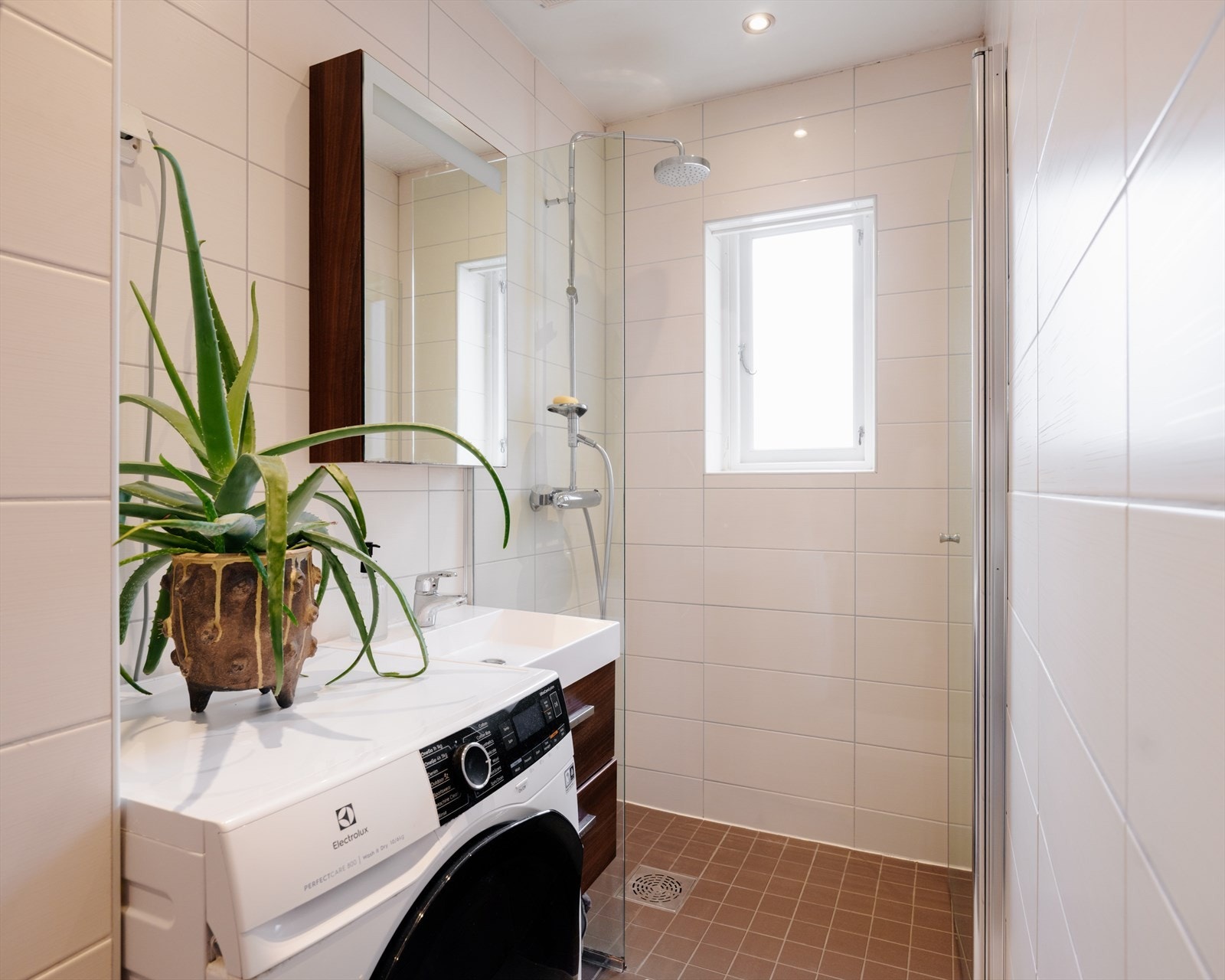 Badet har romslig dusjhjørne, servant med oppbevaring, klosett og opplegg for vaskemaskin. Galleribilde