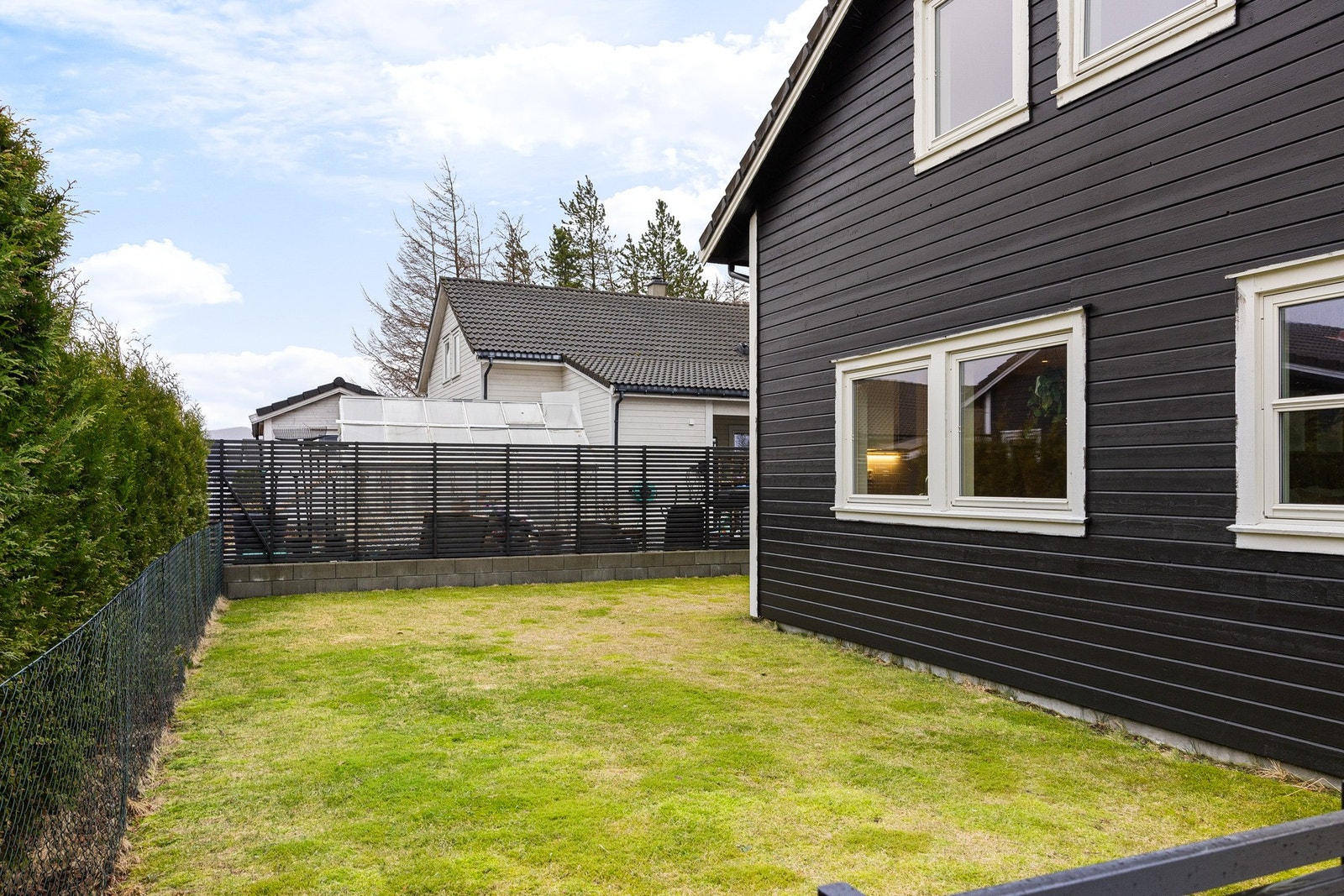 Boligen har også en flott plen som som sammen med terrassen er pent rammet inn med spilerekkverk. Galleribilde