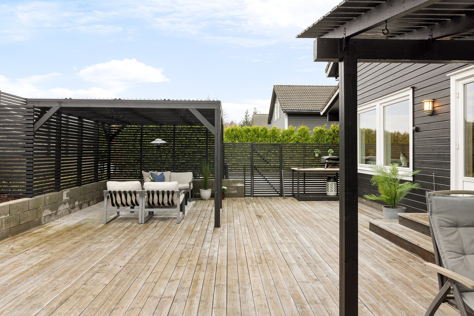 Terrassen er pent opparbeidet med terrassebord, murer og beplatning. Galleribilde