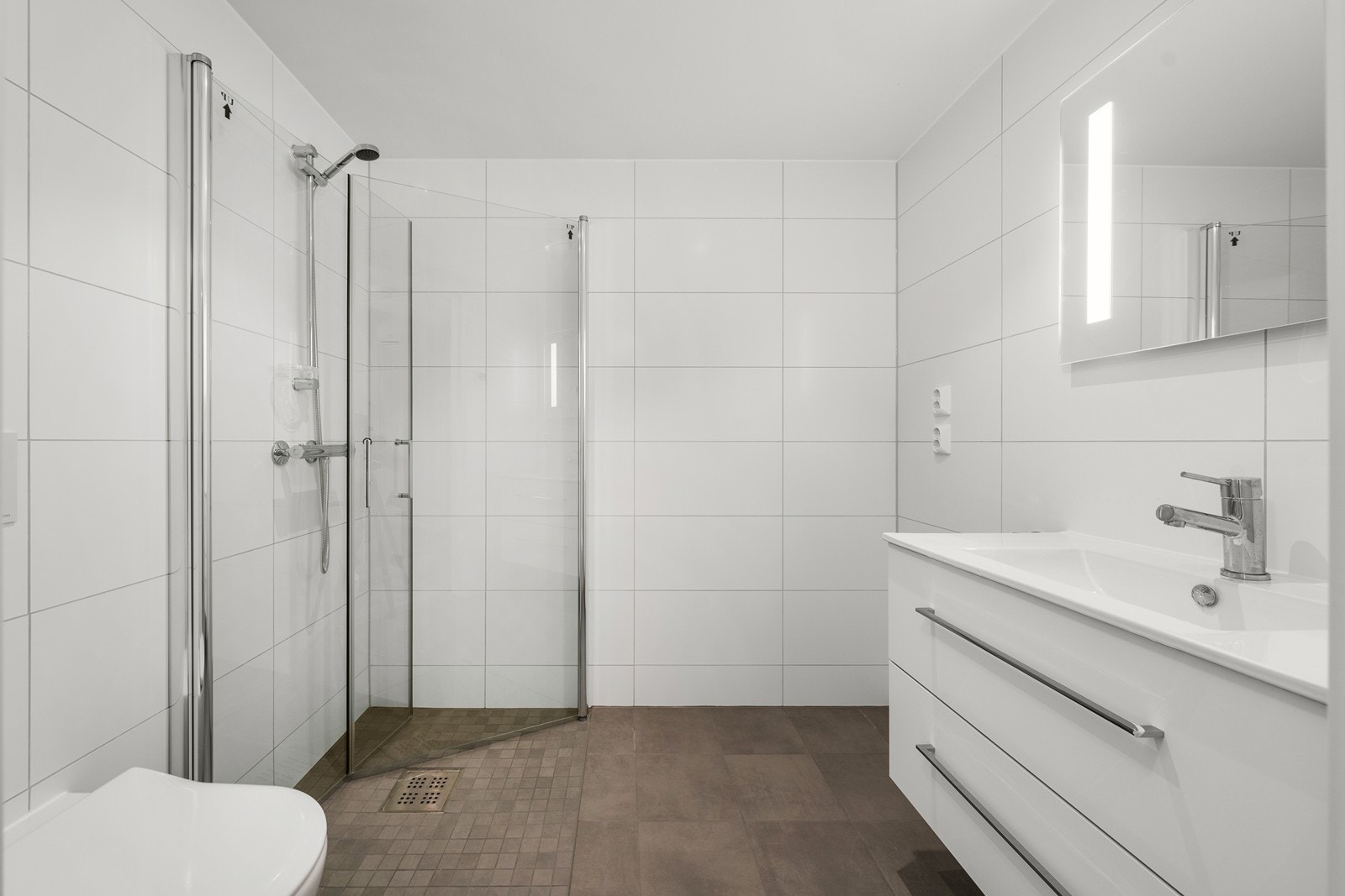 Moderne flislagt bad med opplegg for vaskemaskin. Galleribilde