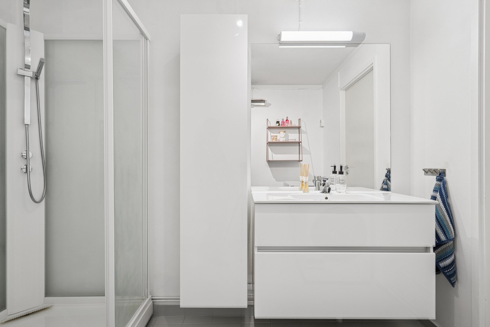 Innredningen består av servant med to romslige skuffer under, høyskap og speil med lys over Galleribilde