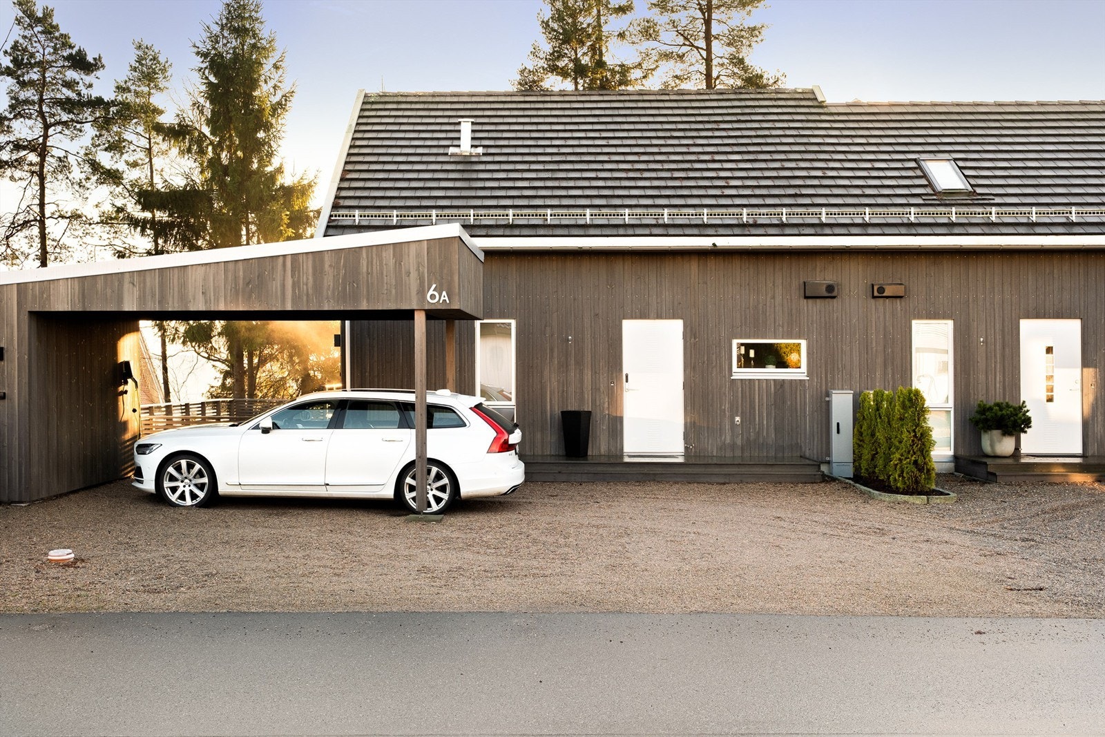 Moderne trefasade med skråtak og integrert carport som gir rene linjer, og innbydende ankomst. Galleribilde