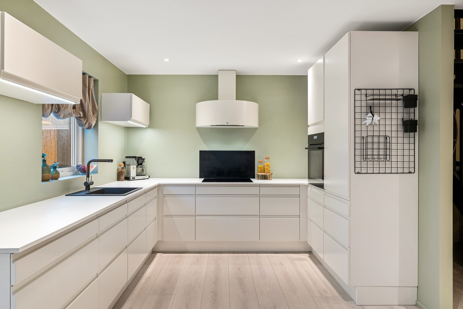 Kjøkkenet byr på effektiv U-form, rikelig benkeplass, velplassert ventilator og en myk fargetone som skaper en rolig atmosfære. Galleribilde